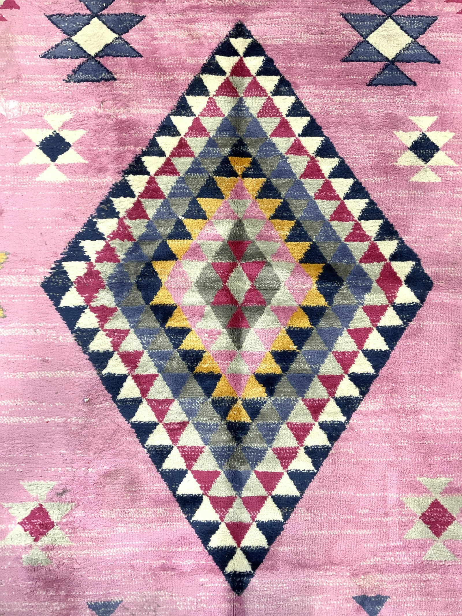 EXCLUSIVE SAMPLE RUGS AMERICA Area Rug: Underside of rug has tag which reads EXCLUSIVE SAMPLE RUGS AMERICA. Rug appears to be wool, possibly cotton. Piece is pink with multi toned geometric detail. Piece measures approx 84 inches long 63 in
