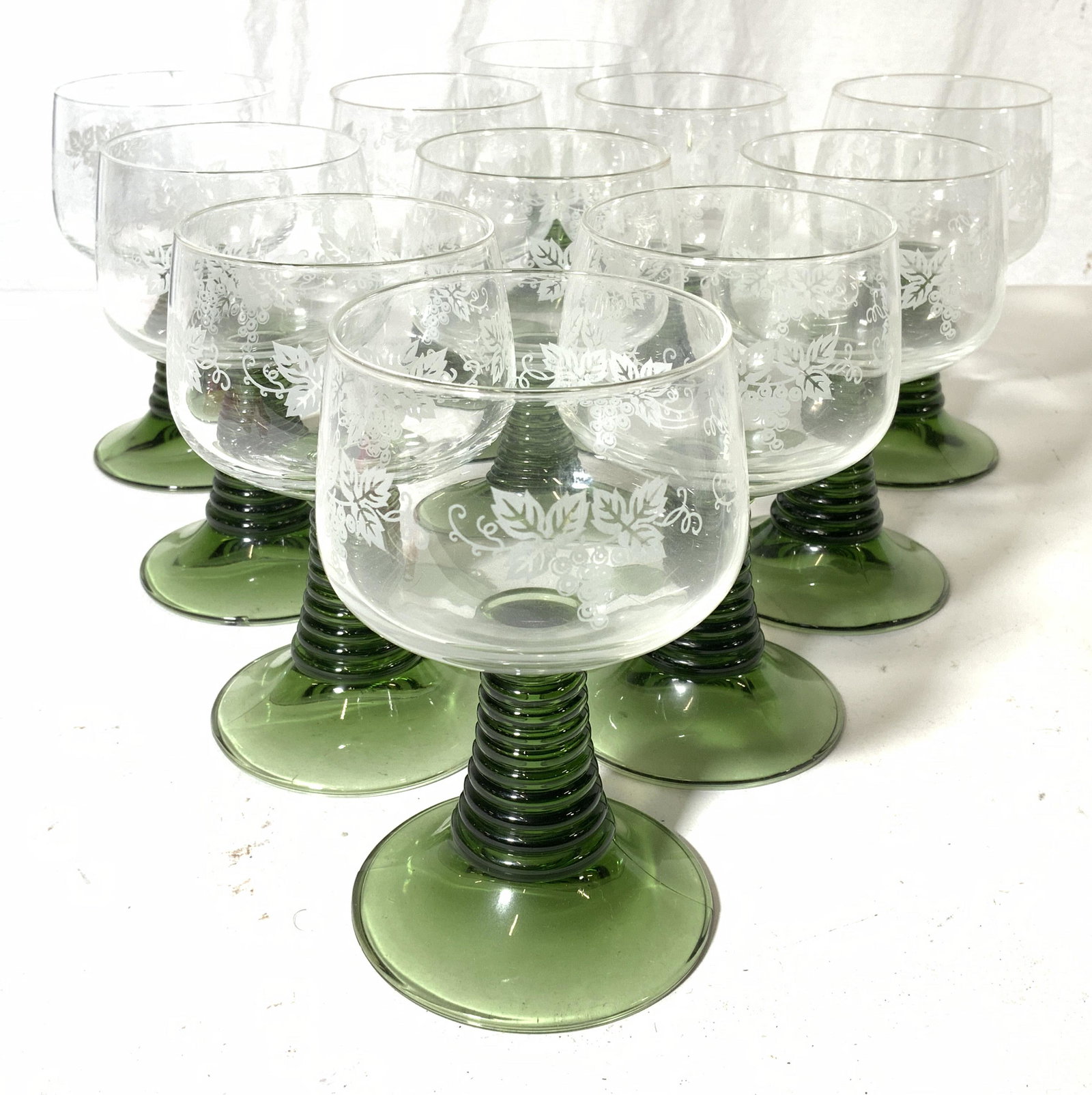 Set 11 Art Glass Goblets W Green Stems: Lot includes 11 goblets. Each appear to possibly be crystal. Basins are clear with frosted floral, leaf & vine detail. Goblet stems are green toned. Piece measures approx 5.5 inches tall 3.5 inches wi