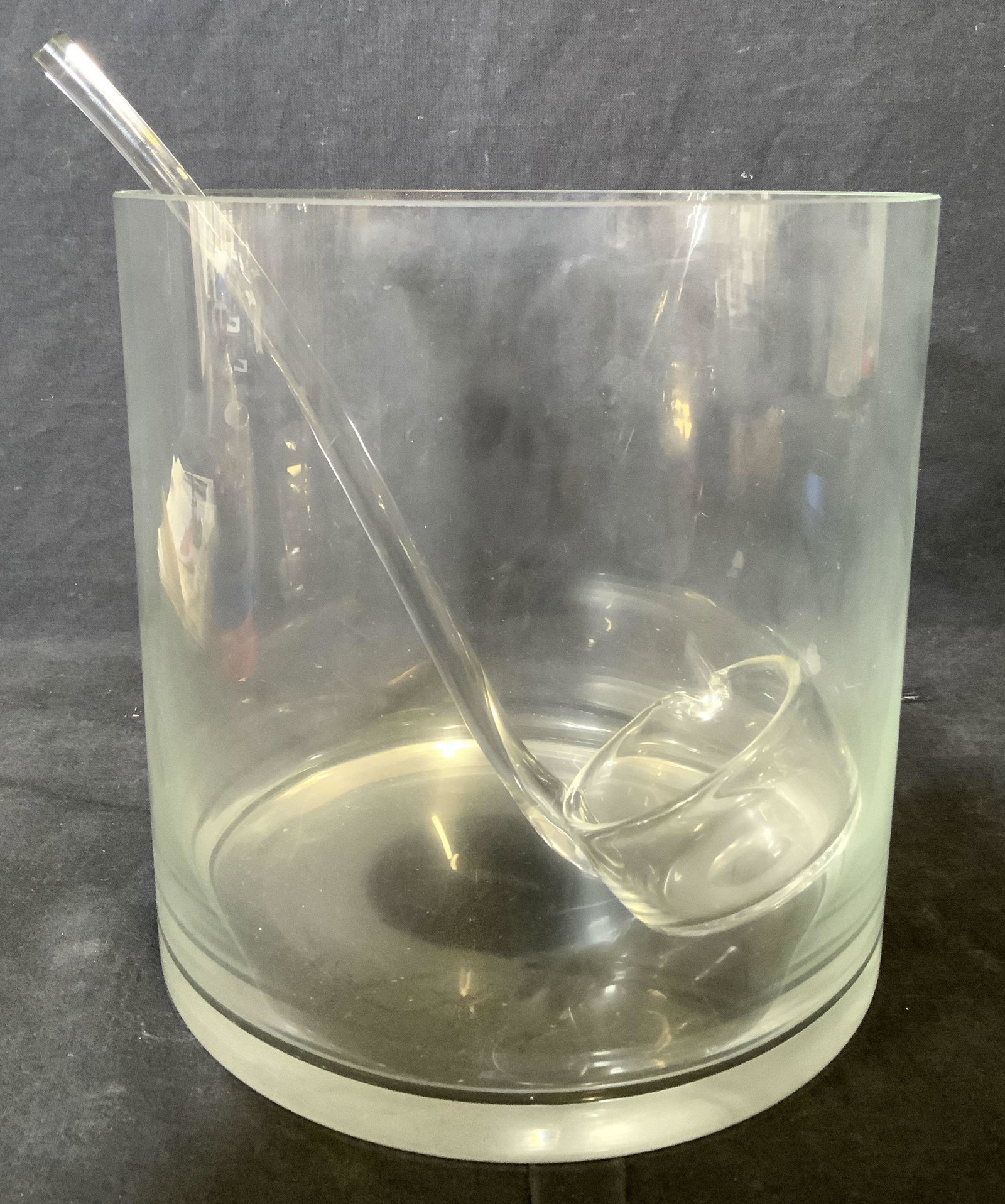 Lot 2 Glass Ladle & Vessel: Lot includes 1 glass ladle & 1 glass vessel. Glass vessel has cylindrical shape. Vessel can be used as up cycled punch bowl. Vessel measures approx 9 inches tall and wide. Ladle, vessel, ladle and ves