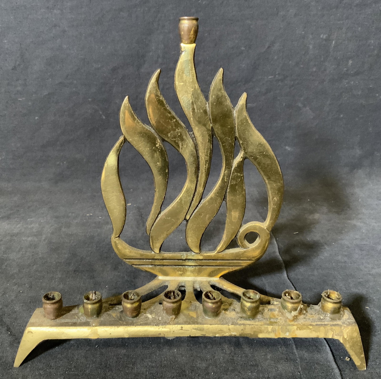 Gold Toned Metal Menorah: Gold toned metal menorah, text to underside reads ‘Skybook’ and ‘Hen Holodon Israel’, surface wear and damage to piece, measures approximately 8 inches tall and 8 inches wide, Gold toned metal