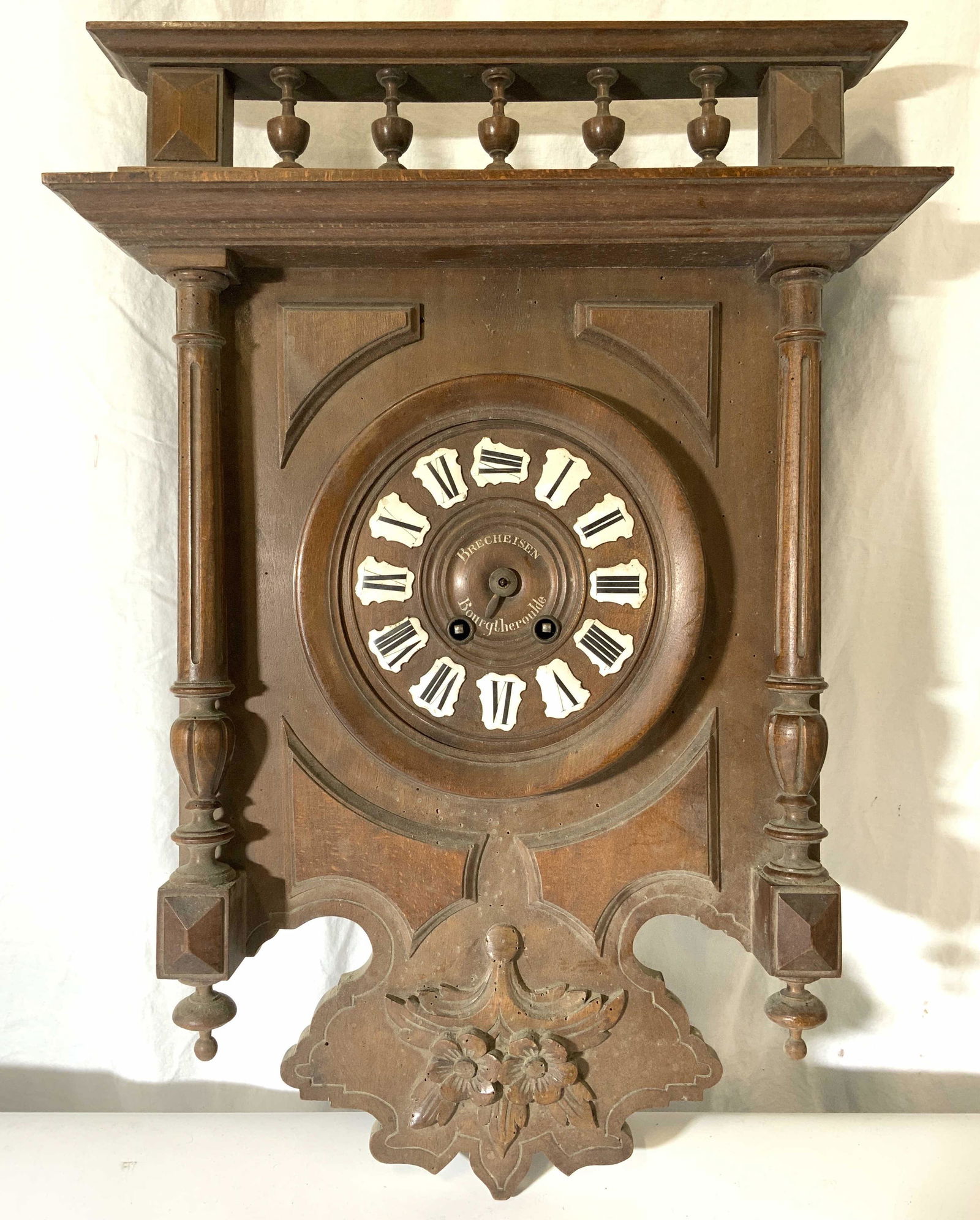 Vintage BRECHEISEN BOURGTHEROULDE Clock: Front of clock face reads BRECHEISEN BOURGTHEROULDE. Piece is brown toned and wooden. Piece is vintage possibly antique. Piece has intricately carved wooden finial, pillar, floral & leaf structures. P