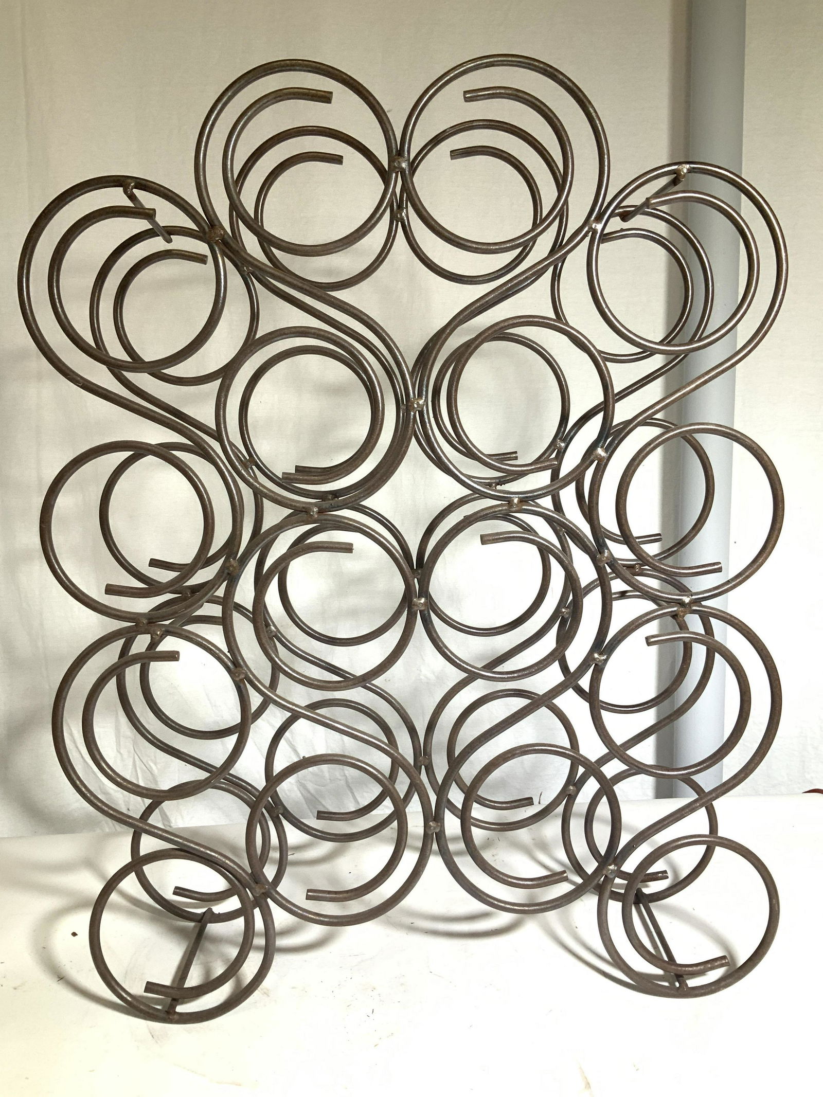 Floor Standing Metal Wine Rack, 28 in. Tall: Circular Pocket wine rack with 16 wine bottle pockets, heavy weight metal, possibly coated iron, measures 28 in. Tall x 21.25 in. Wide x 6 in. Deep. Can be for floor or table. Standing wine rack, floo