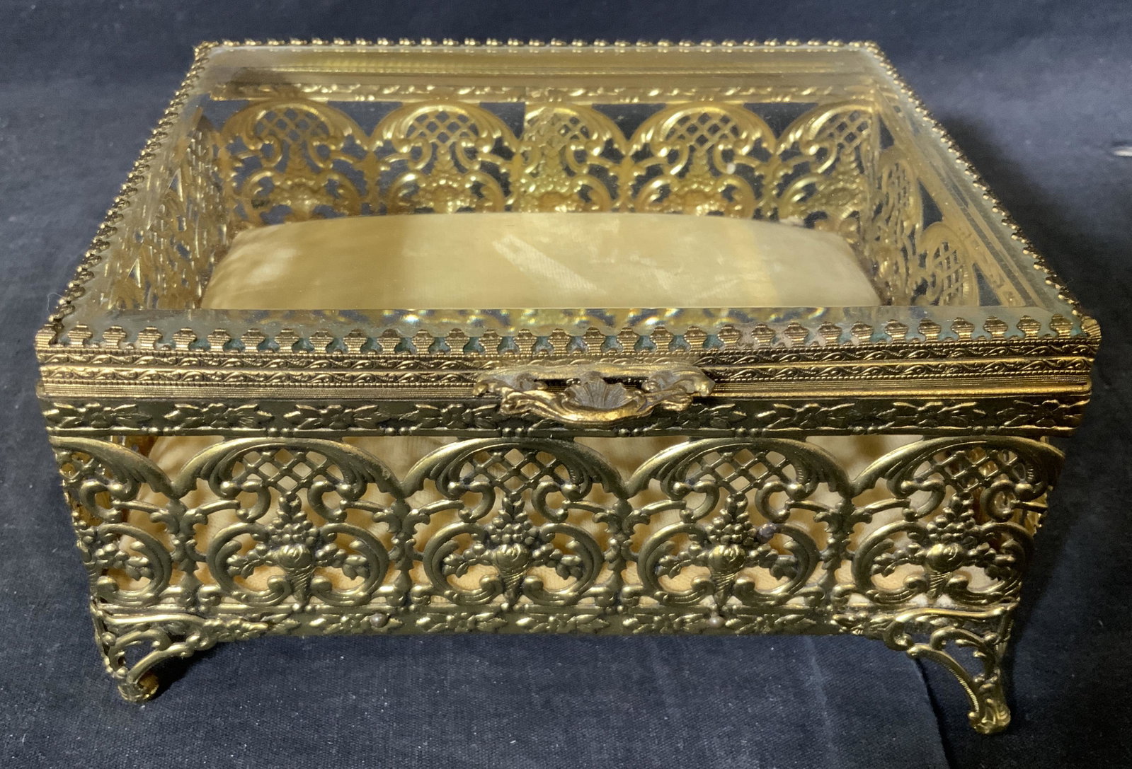 Gold Toned Metal Trinket Box: Gold toned metal trinket box, base of box lined with a champagne colored velvet, lid to box is a clear glass, some indents in velvet from age, box measures 6.75 inches by 3.5 inches by 5.5 inches, sur