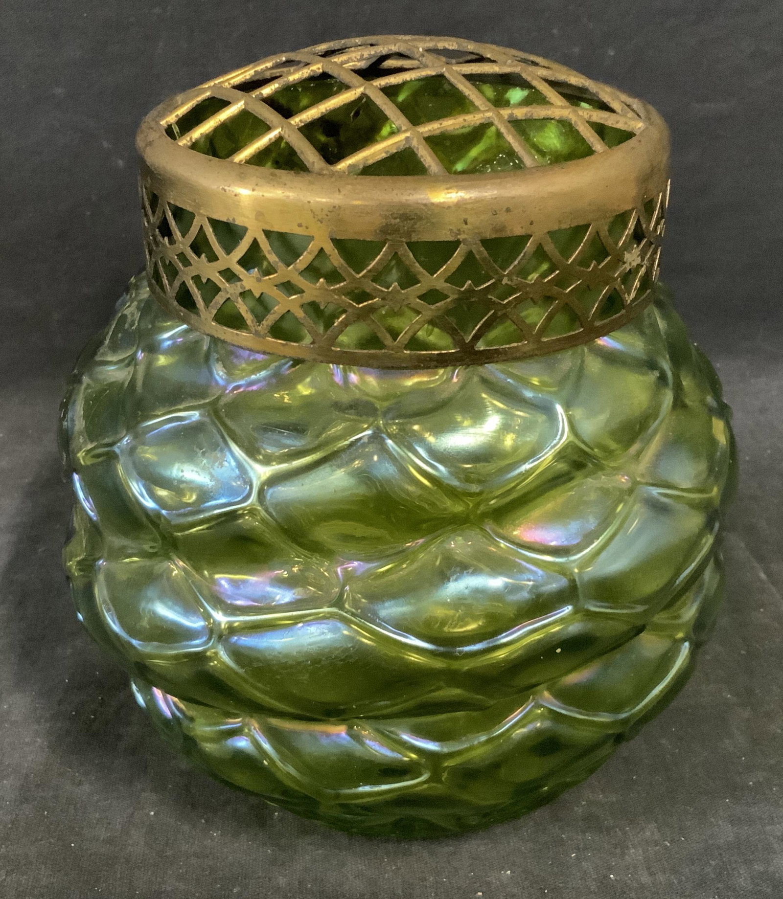 Green Pearlescent Art Glass Container: Green pearlescent art glass container, lid to container is grated and made of a brass toned metal, container made of a pearlescent green art glass with a fish net pattern to the surface, piece measure