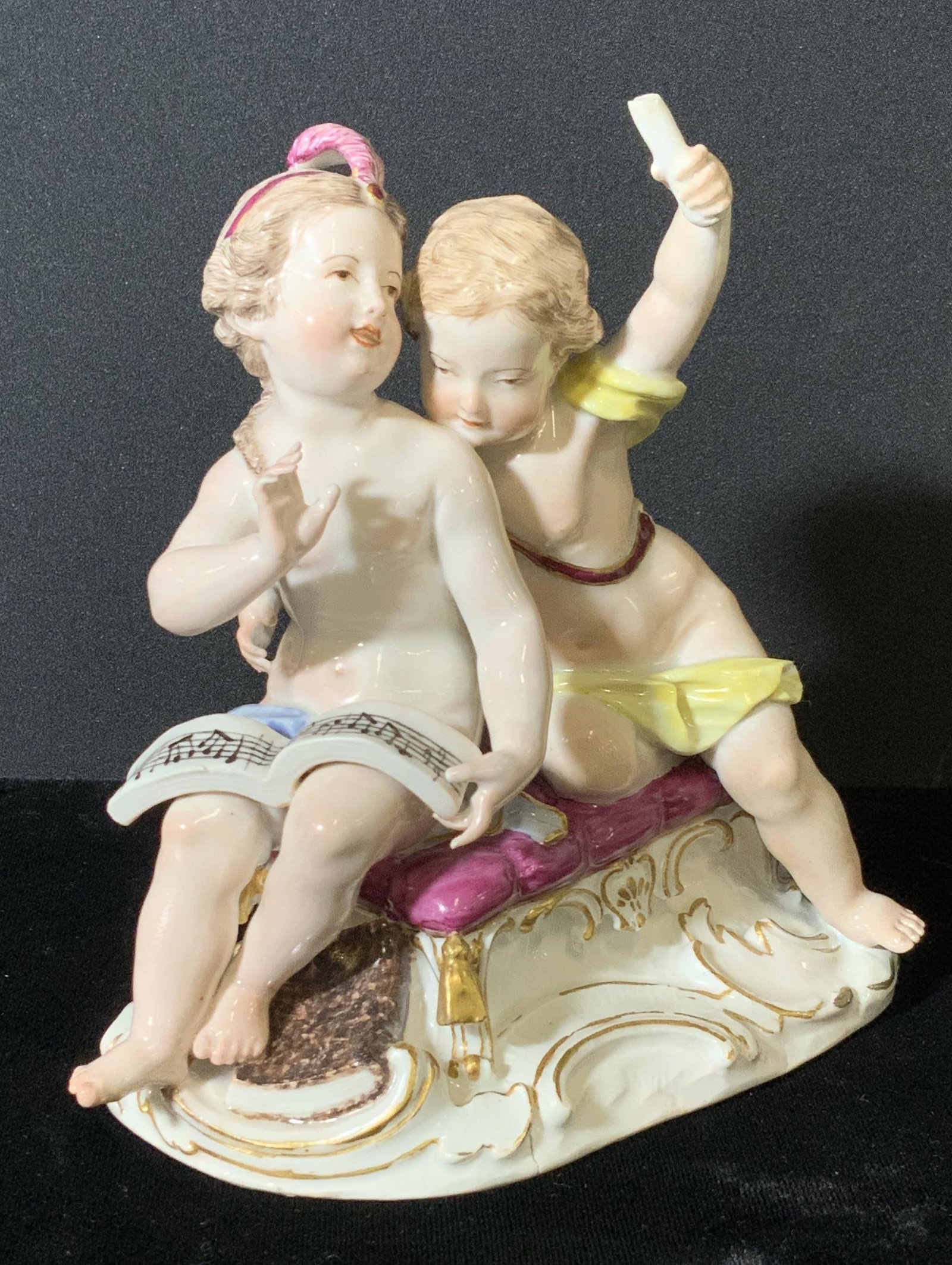 19th C Hallmarked MEISSEN Porcelain Figural: Decorative MEISSEN Porcelain statuette of boy and girl in nude looking over music notes. Both are sitting on a stool with a violin and horn by their sides. Hand painted, accented with gilt, Meissen sw