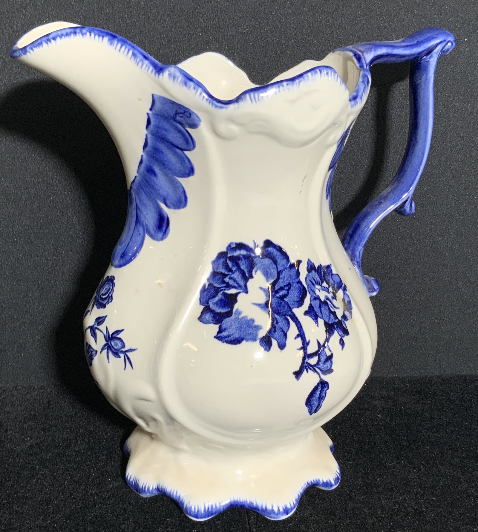 Vintage STAFFORDSHIRE English Ironstone Pitcher: A collectible blue and white ironstone pitcher. Piece is glazed and features hand painted patterns and transfer florals. The rim and base of the piece are scalloped. The underside of the piece is trad