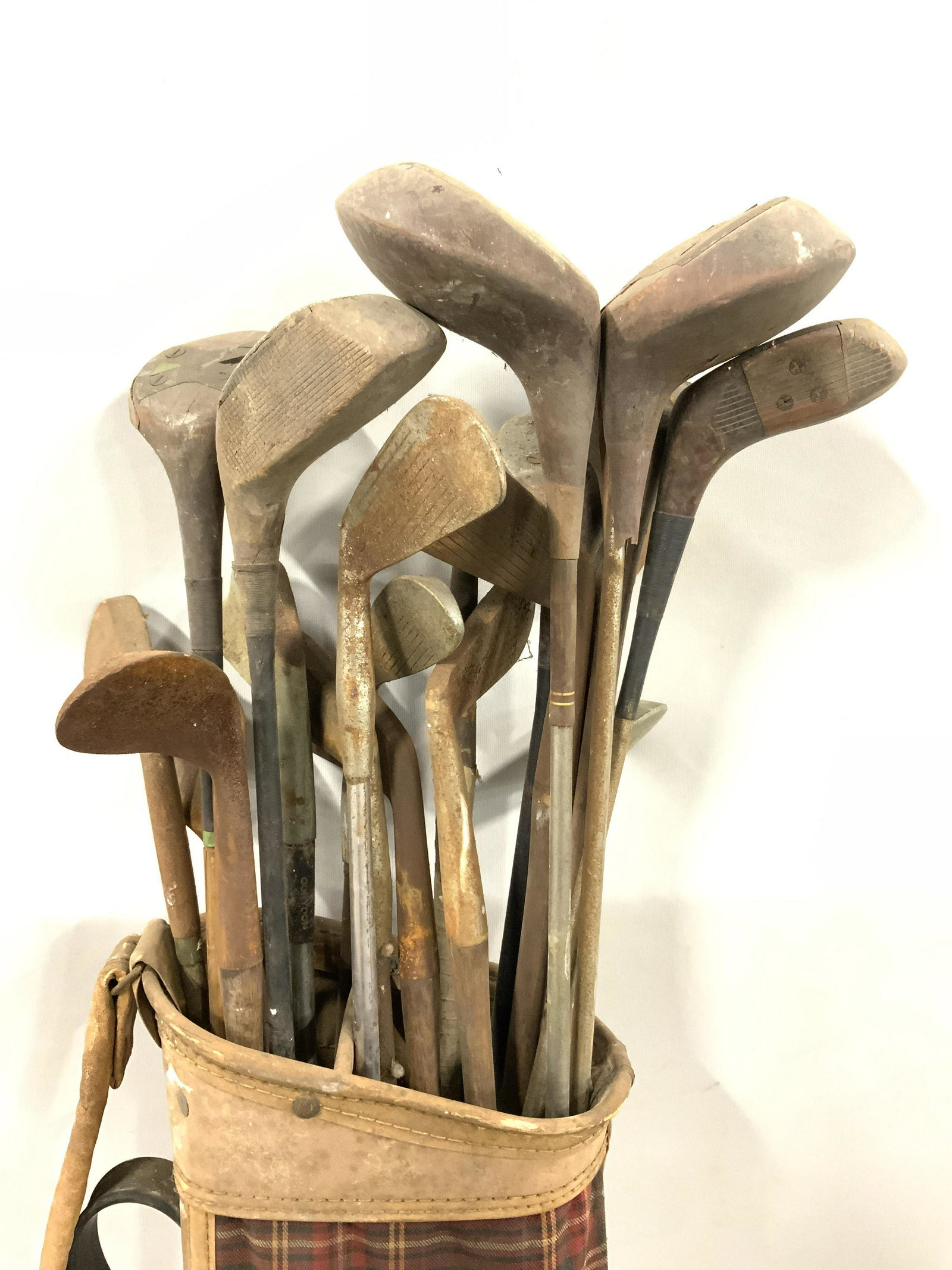 Lot 19 Vtg & Antique Golf Clubs & Bag: Lot includes 18 golf clubs & 1 bag. Clubs include some irons, 1 woods, drivers & more. Golf bag has plaid detail. Some areas of bag appear to be leather. Bag measures approx 31 inches tall 9 inches wi
