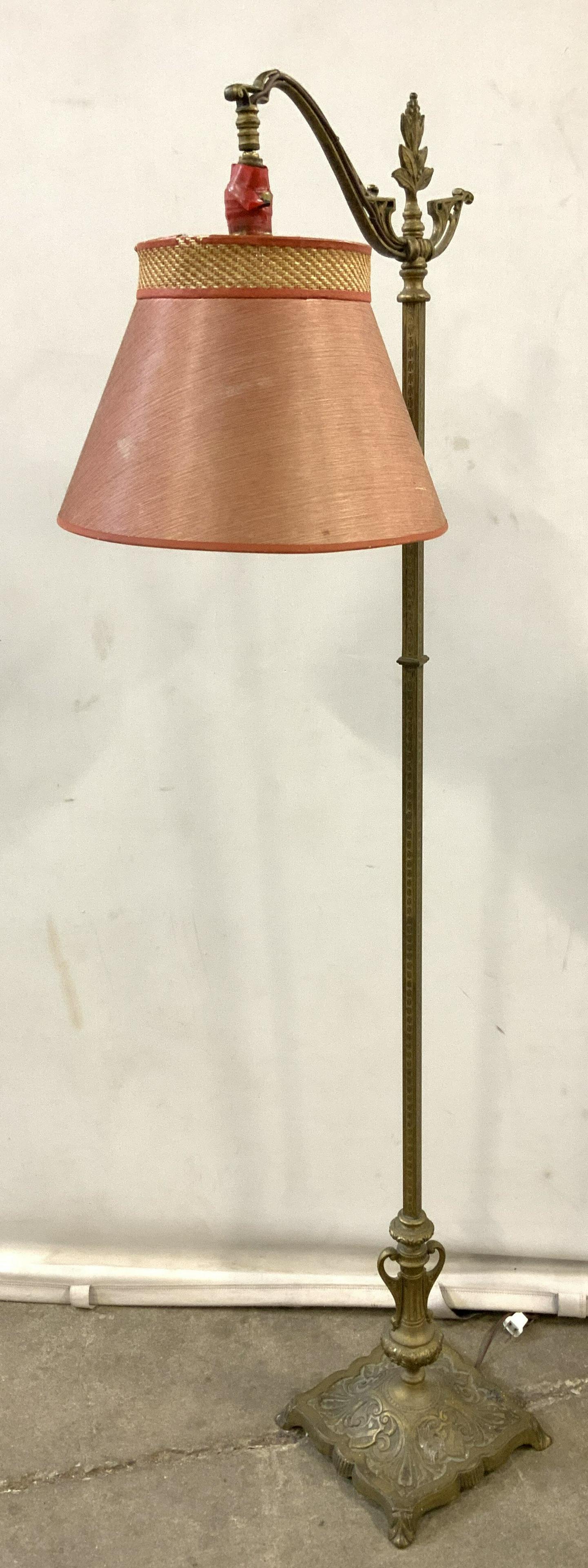 Vintage Brass Floor Lamp w Shade: Vintage Brass Floor Lamp, possibly antique. Base decorated with cast shield and leaf detailing, leaf and berry detailing cast into finial. Red lamp shade wrapped in thread. Socket has loosened and nee