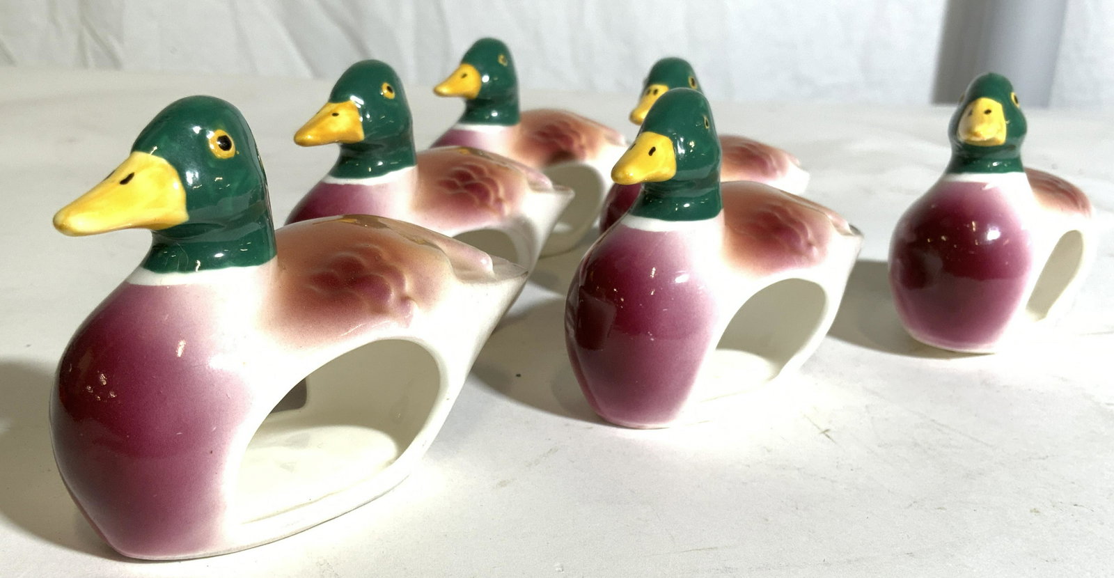 Set 6 PIA Porcelain Mallard Duck Napkin Rings: Underside of each piece reads PIA BONE CHINA PHILIPPINES. Napkin rings are porcelain and shaped like mallard ducks. Lot includes 6 napkin rings. Each piece appears to possibly be hand painted. Each pi