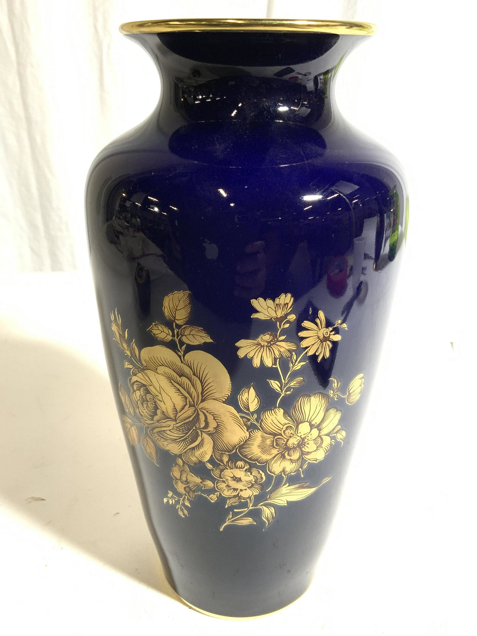 KPM Floral Detail Porcelain Vase: Underside of piece is marked ROYAL PORZELLAN BAVARIA KPM GERMANY. Exterior is blue with gold toned floral vine and leaf detail. Interior is white toned. Piece has gold toned rim. Vase measures approx 