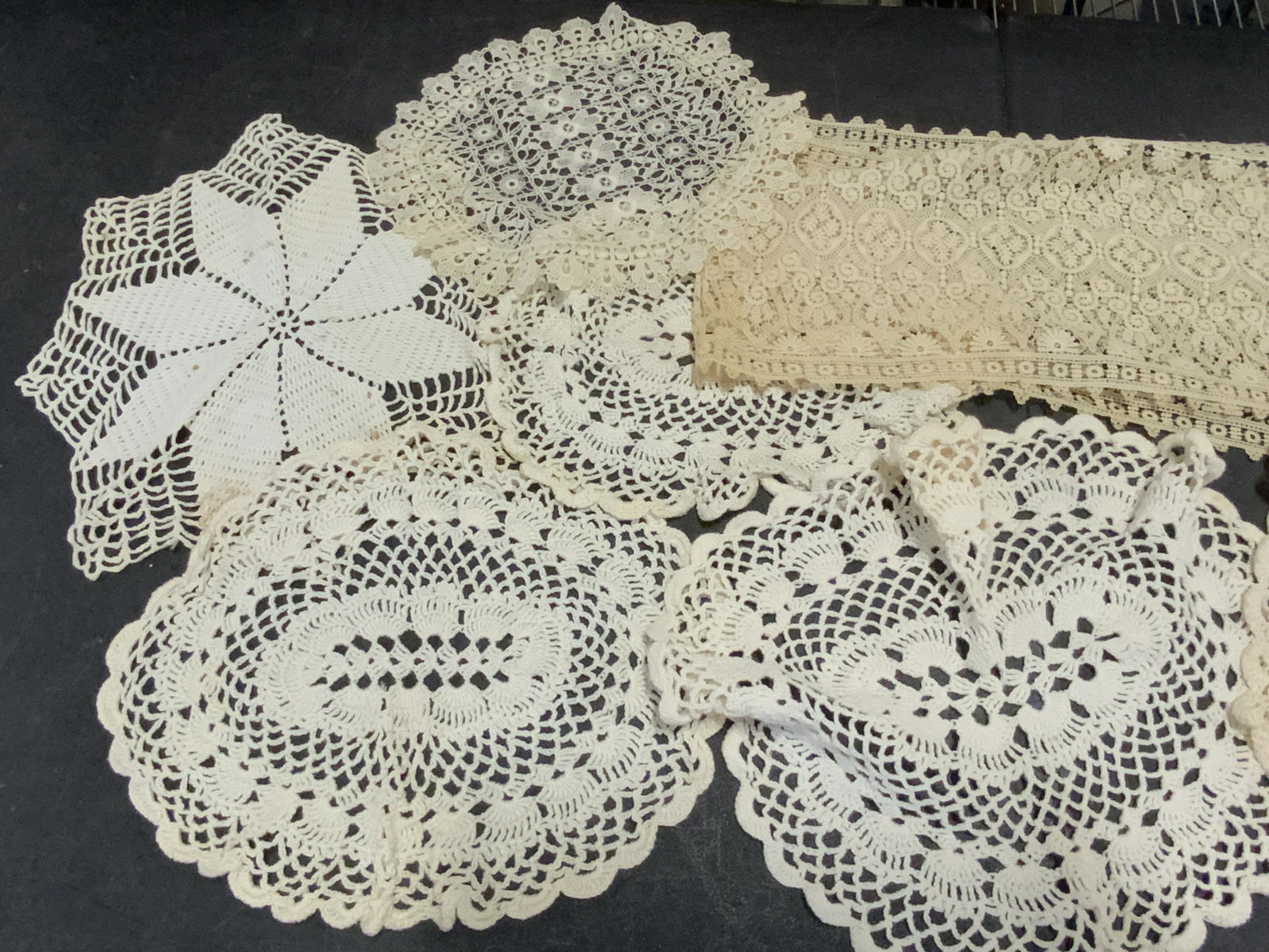 Lot 12 Vintage Crochet Doilies & Lace Scarf: A vintage lot of eleven crochet doilies and one lace scarf. Pieces appear to be handmade. Primarily white and off white hues. Largest doily approx 10L x 12W in. Lace scarf, crochet doilies, arts and c