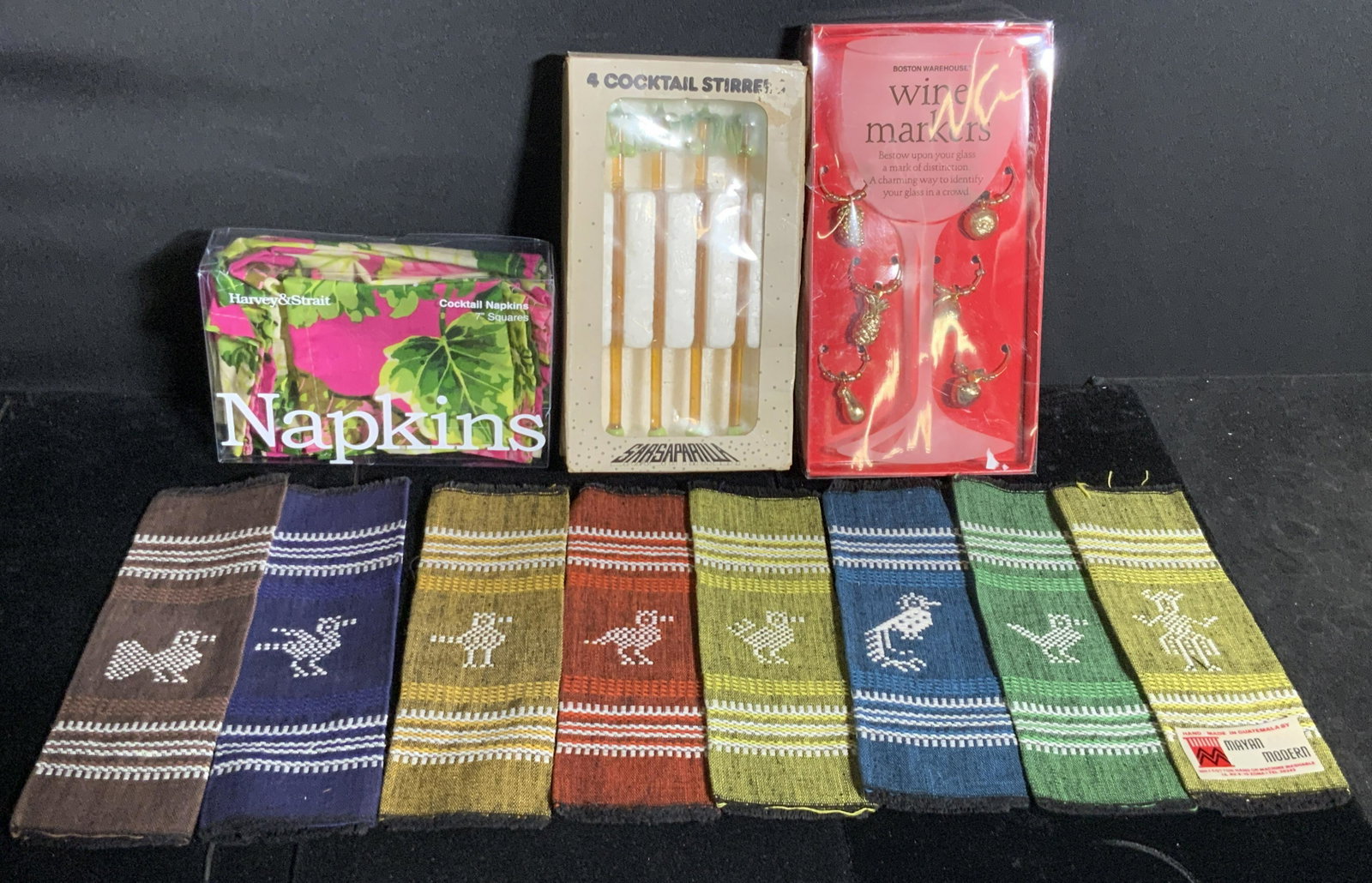 11pc Barware & Tabletop Decor, Napkins & More: A lot of fabric cocktail napkins and bar accessories. The lot includes eight Mayan Modern cotton napkins, one package of wine markers, a package of cocktail stirrers, and a box of Harvey & Strait cock