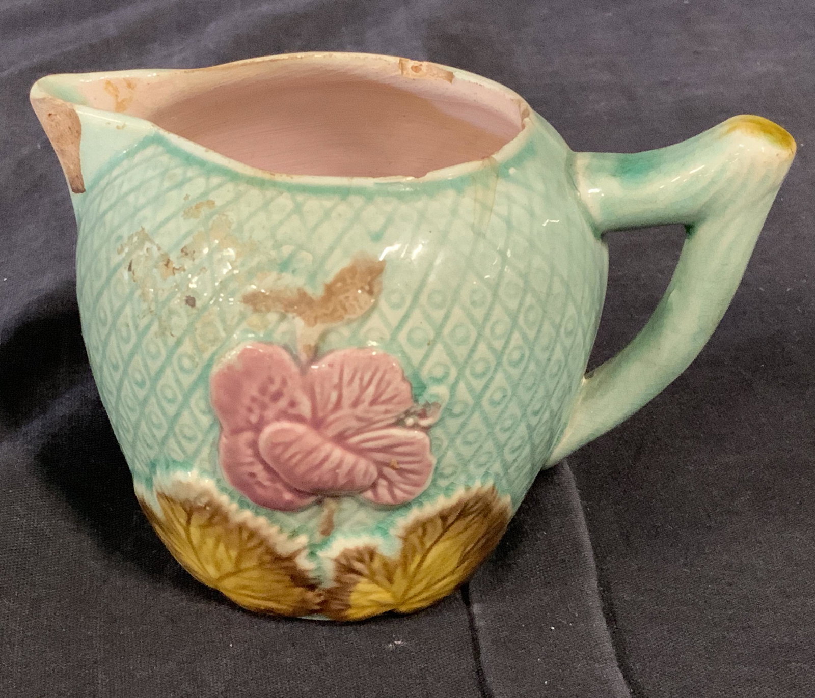 Early Majolica Porcelain Creamer Cup: Early majolica porcelain creamer cup, no apparent inscriptions or markings, subject a mostly teal colored creamer cup with pink flowers and yellow leaves decorating the surface, surface wear to piece,