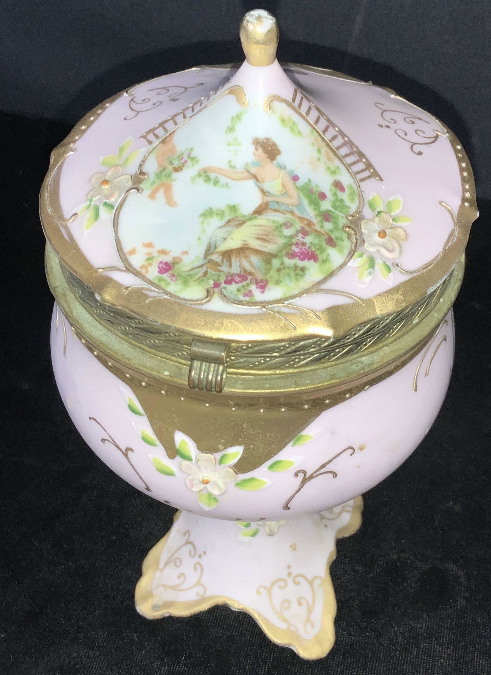 Vintage & Signed Porcelain Lidded Pedestal Chalice: Hand painted a matte pink with gilt and brass hinged lid. Paste up Florals and Cartouche of European Boy bring flowers to lady. Paste up gold scroll decor, Interior all white porcelain. Underside stam