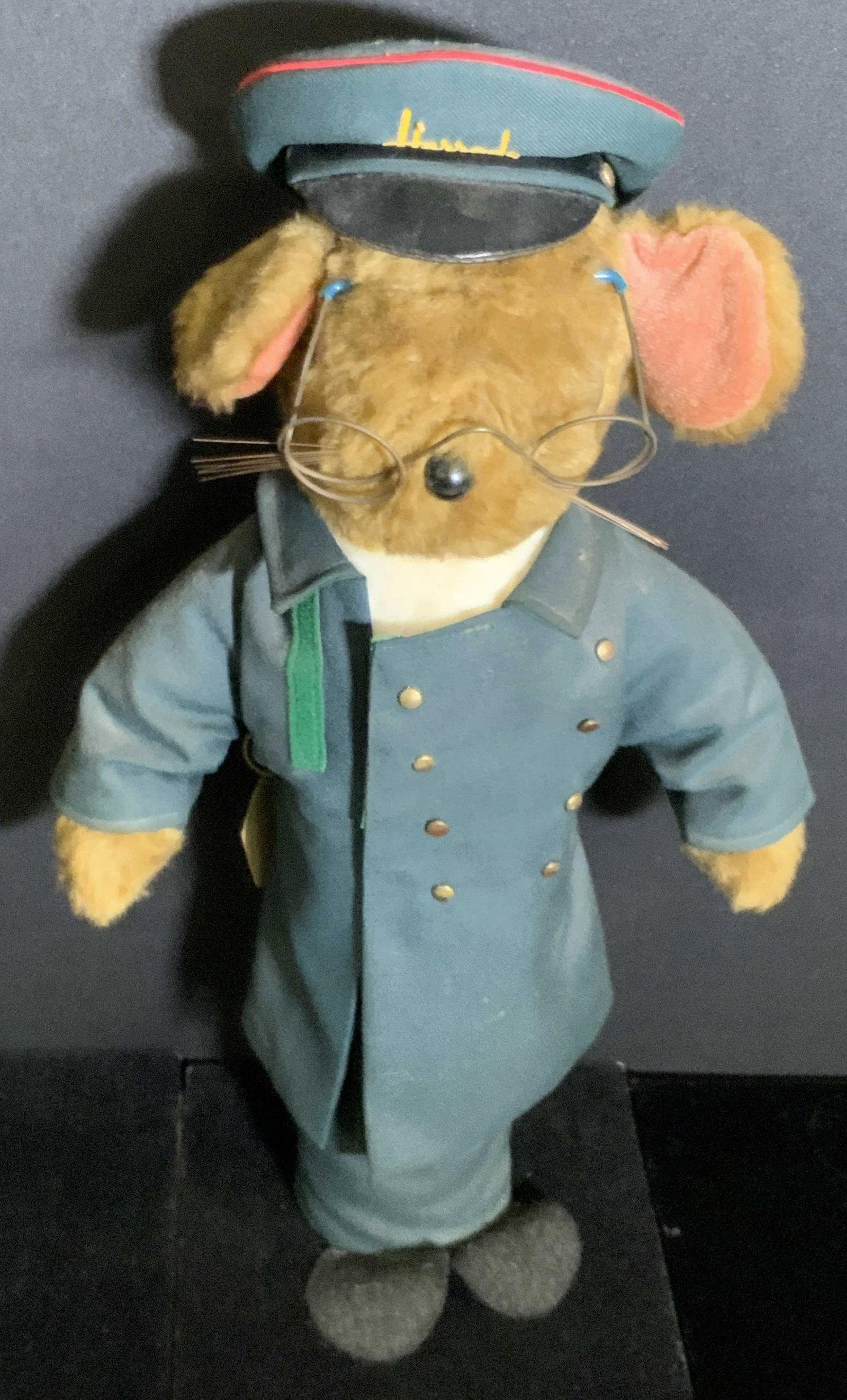 Vintage HARRODS ORIGINAL DOORMAN Doorstop: A vintage doorstop crafted to resemble a mouse wearing a doorman’s uniform. The uniform is primarily deep green hued. The cap, which is removable, reads Harrods. A tag affixed to the reverse reads H