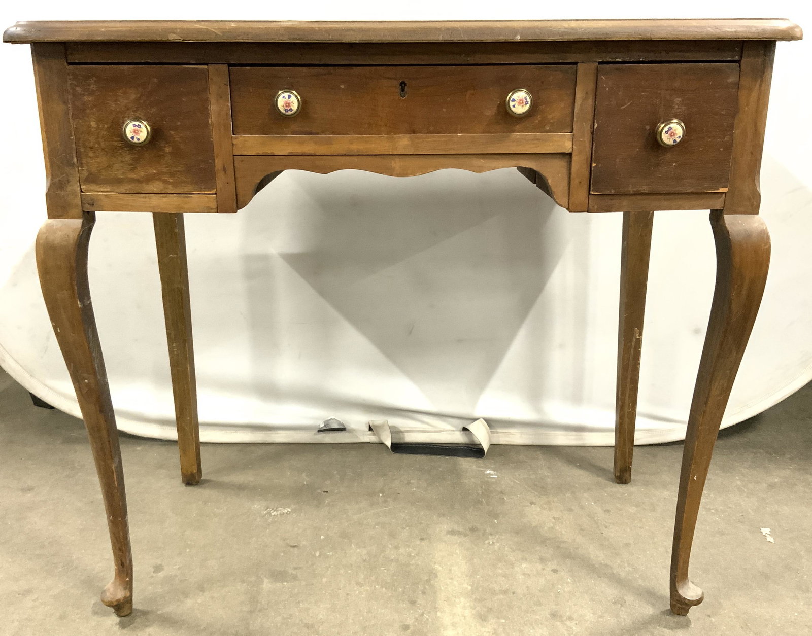 Antique Cabriole Leg Desk W Drawer: Desk is antique and wooden possibly hand crafted. Piece has 3 drawers each with hand dovetailing. Desk has 2 front cabriole legs. Piece has Queen Anne style. Each drawer has floral detailed knob style