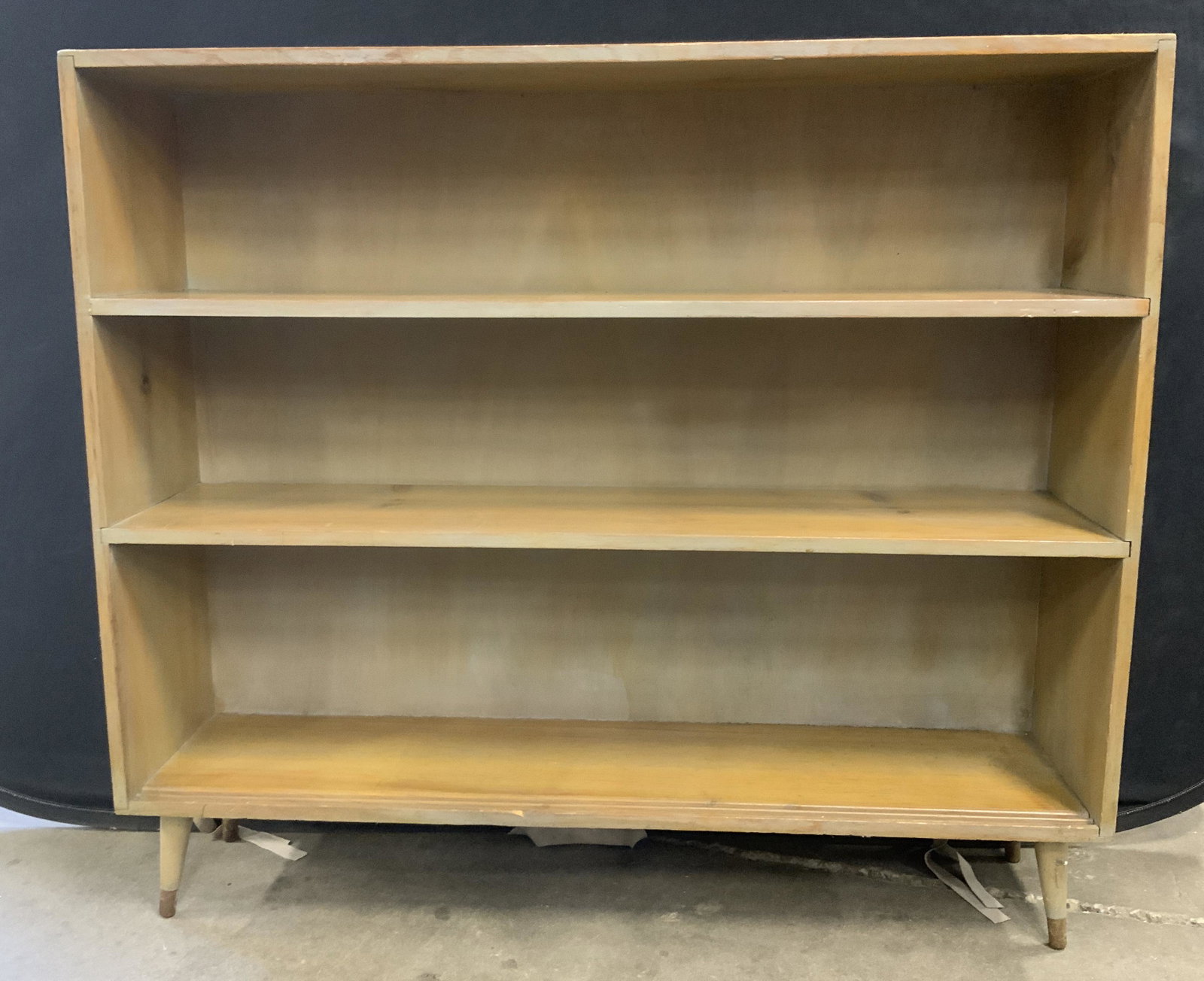 Vintage Wooden Shelves: Vintage wooden shelving. Rests on four legs, all legs are capped with, what appears to be, brass. Loss is present, doors meant to be affixed to bottom shelf are absent. Wear is consistent with age and
