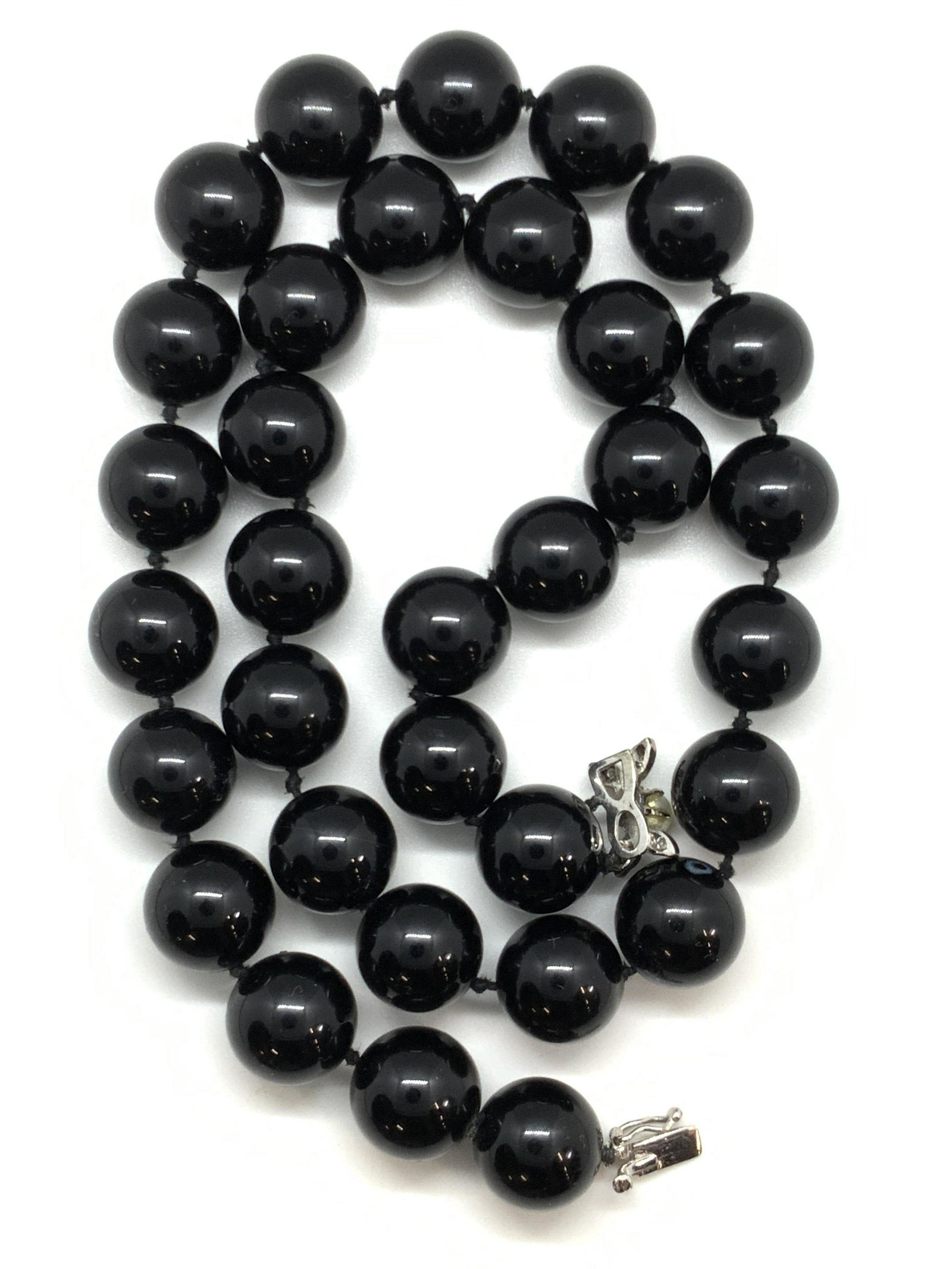 4K White Gold & Black Glass Beaded Necklace: A black glass beaded necklace strung on black string. The white gold clasp is marked 4K. A pearlescent bead and crystals accent the white gold clasp. Box clasp closure. Length approx. 20 inches. 4K go