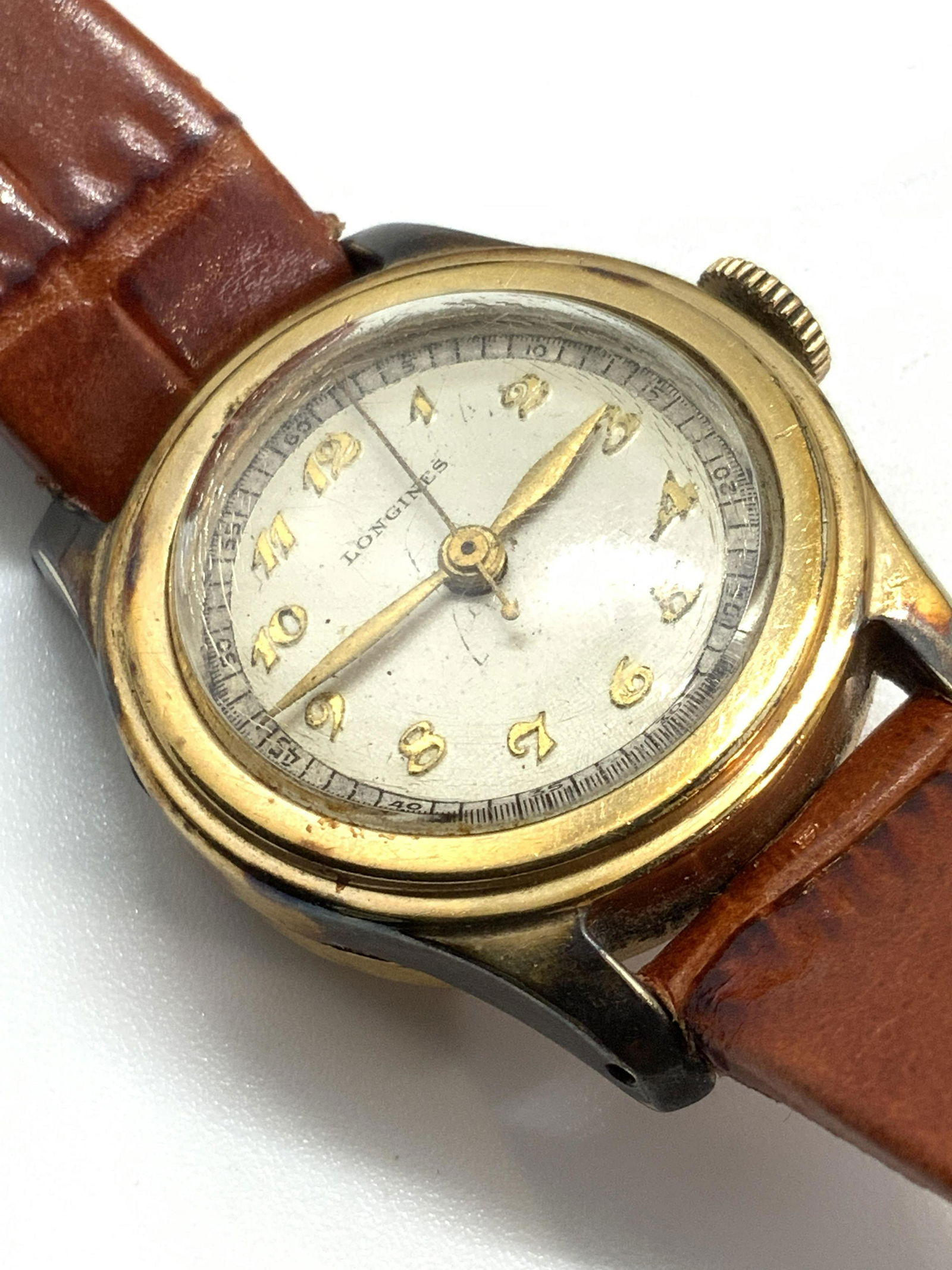 LONGINES Leather Hadley Roma Ladies Watch: A genuine leather reptile style ladies watch. The watch face is crafted from a gold tone metal. Watch face reads Longines. Watch band is a reddish brown hue. Interior of watch band reads Genuine Leath