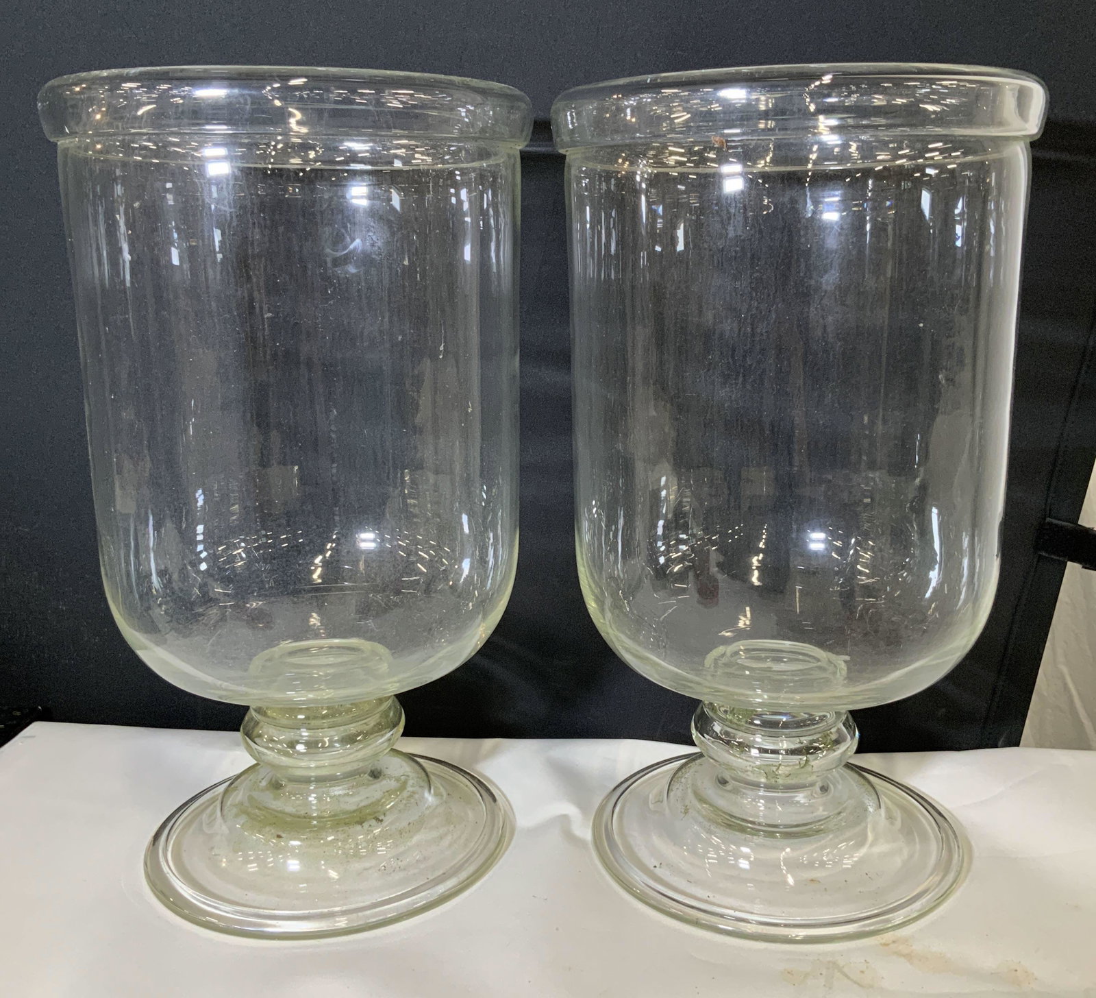 Pair Minimalist Thick Glass Pedestal Centerpieces: Use these vessels for many Decorative purposes, from oversized candle holders to indoor garden accessories, covered front step statuary, indoor planters, holiday decor with lighting and beading access