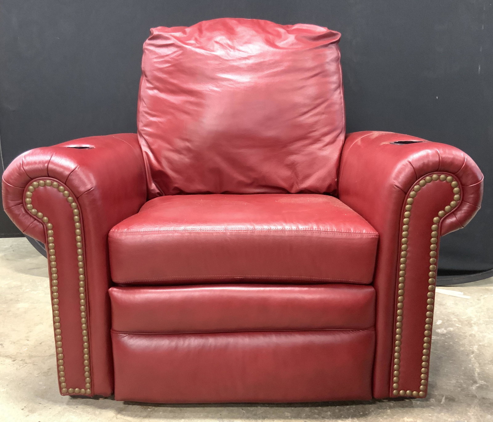 BARCALOUNGER Red Leather Reclining Theatre Chair: Underside has tag which reads BARCALOUNGER CORPORATION. Interior of cup holder reads BECKSON. Chair is red toned and leather. Piece has 2 black toned cup holders. Front of piece has gold toned nailhea