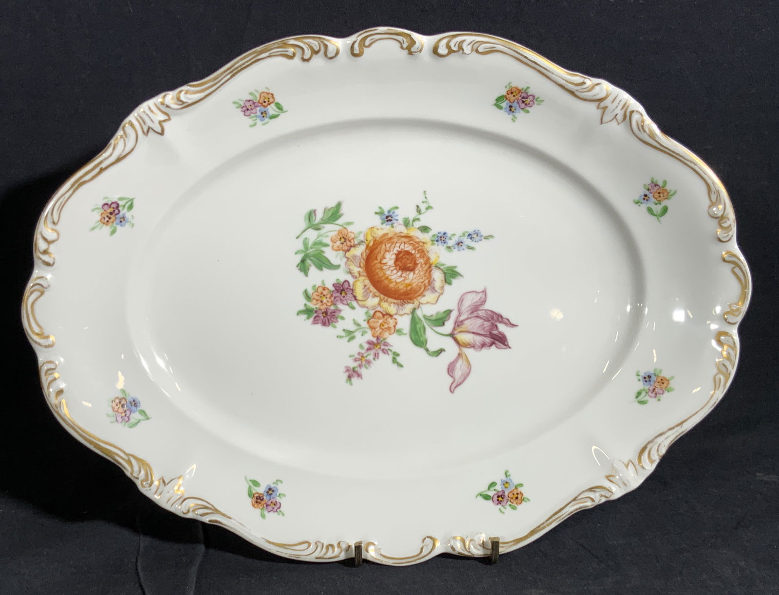 ROSENTHAL Hand Painted Porcelain Platter, Germany: A hand painted porcelain platter decorated with floral motifs and gilt line work. The piece is primarily white with pops of springtime greens, purples, blues, and more. Some wear to paint. Chip to und