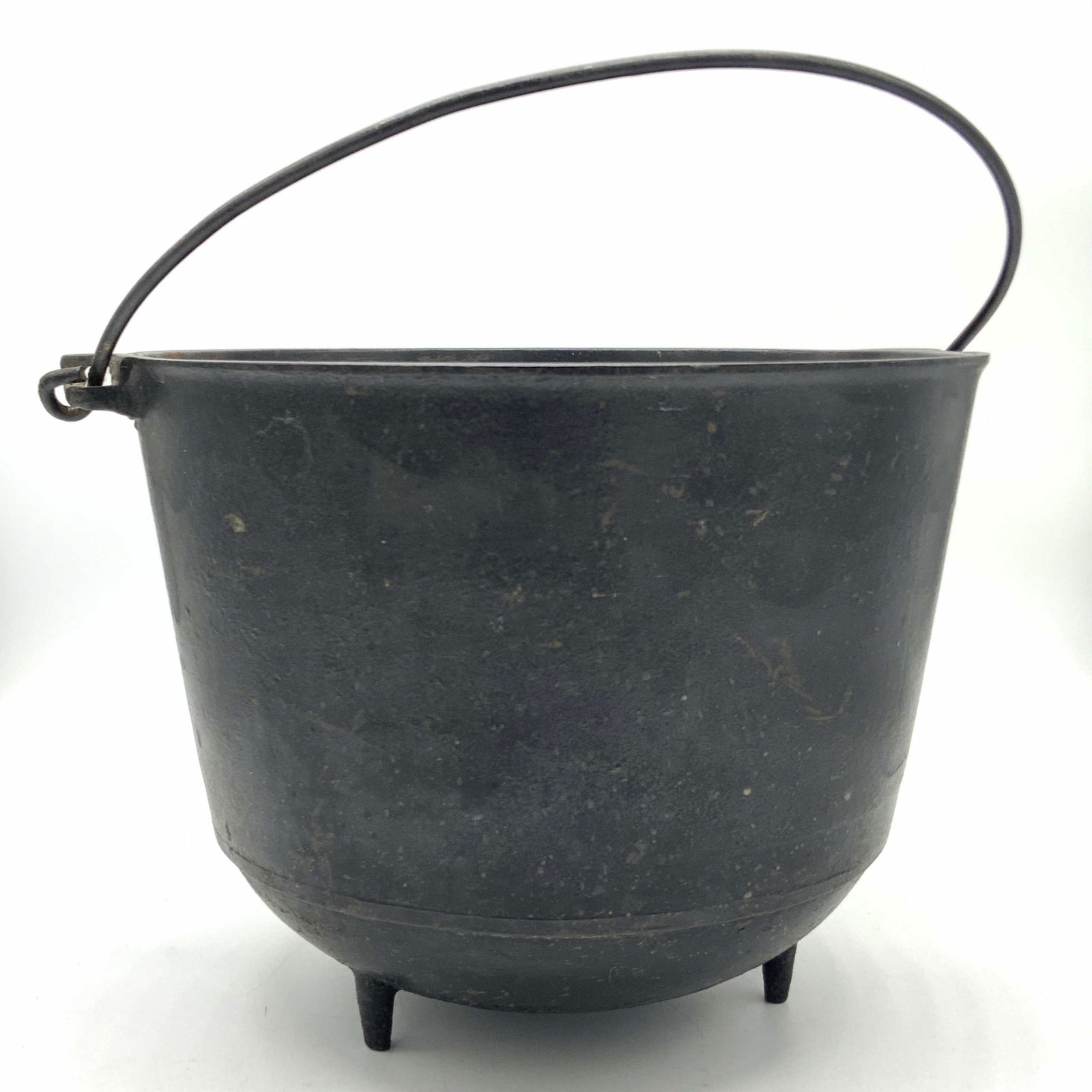 ERIE Colonial Black Cast Iron Hearth Fireplace Pot: A Cast Iron Pot, possibly from the mid 1800s, with three pronged legs. The piece possesses a top handle. The underside reads Erie. Piece has some surface wear consistent with age and use. Crack, scrat