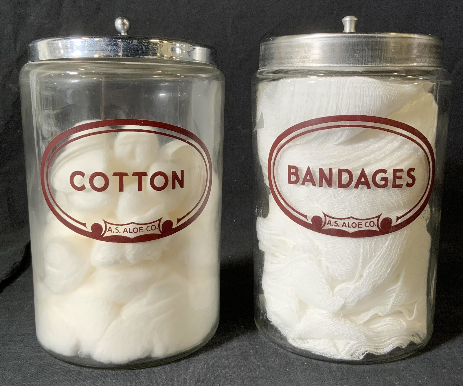 Pair Vintage AS ALOE CO Apothecary Jars: Pair Vintage AS ALOE CO Apothecary Jars, inscriptions to pieces read ‘Cotton AS Aloe Co Glasco Chrome’, ‘Bandages AS Aloe Co Crafco Stainless Taiwan’, both jars measure 7 3/8 inches tall x 4 1