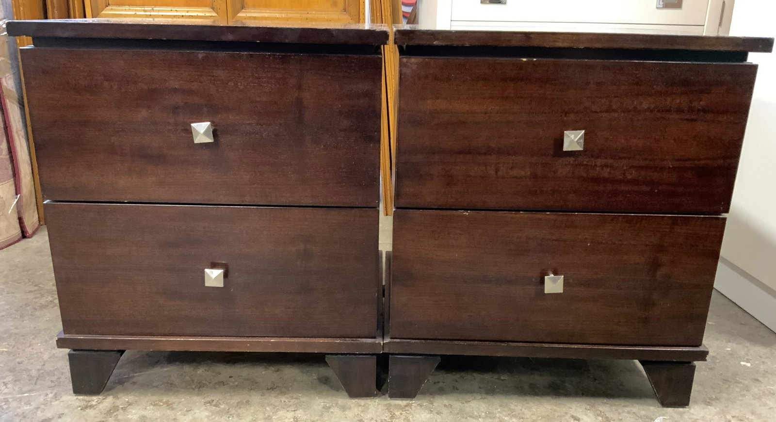 Pair LIGNA Nightstands: Backside has tag which reads LIGNA. Each has a brown mahogany tone and appears to be wooden possibly veneer. Each nightstand has 2 drawers each with silver toned square shaped metal handles. Each meas