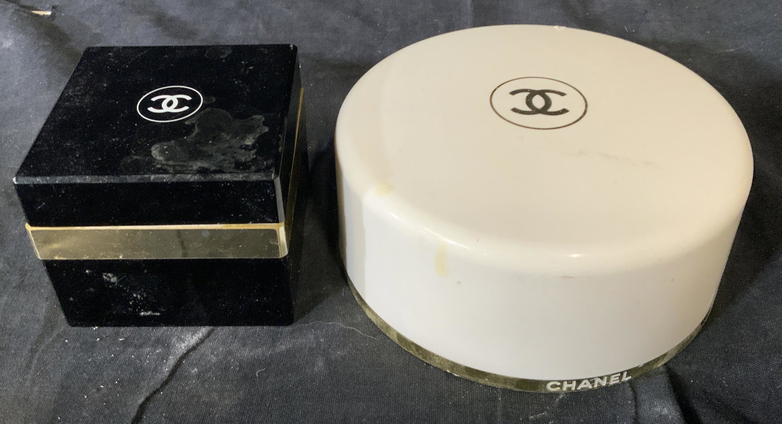 Pair of 2 CHANEL Powder Boxes: Pair of 2 CHANEL Powder Boxes, inscriptions read ‘CHANEL’, larger piece measures 2 1/4 inches tall x 5 1/4 inches in diameter, smaller piece measures 2 5/8 inches tall x 3 inches wide, surface wea
