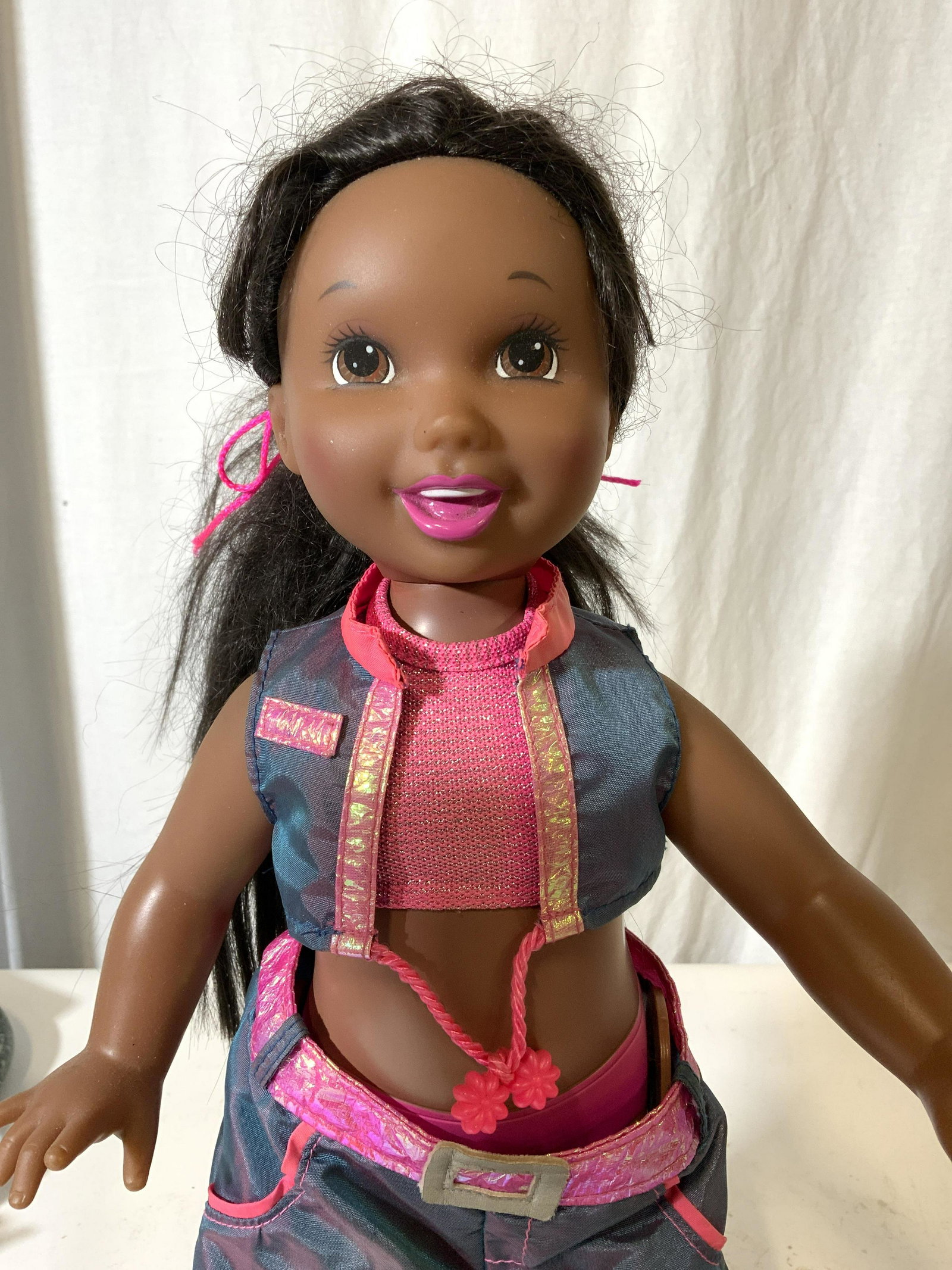 DANCIN DEBBI African American Mattel Doll: Very Cute Doll, Mattel’s 2000 DANCIN’ Debbi African American Mechanical Doll. She is wearing an iridescent outfit, matching pants and crop top. She has brown eyes and pink lips and wears Sketchers