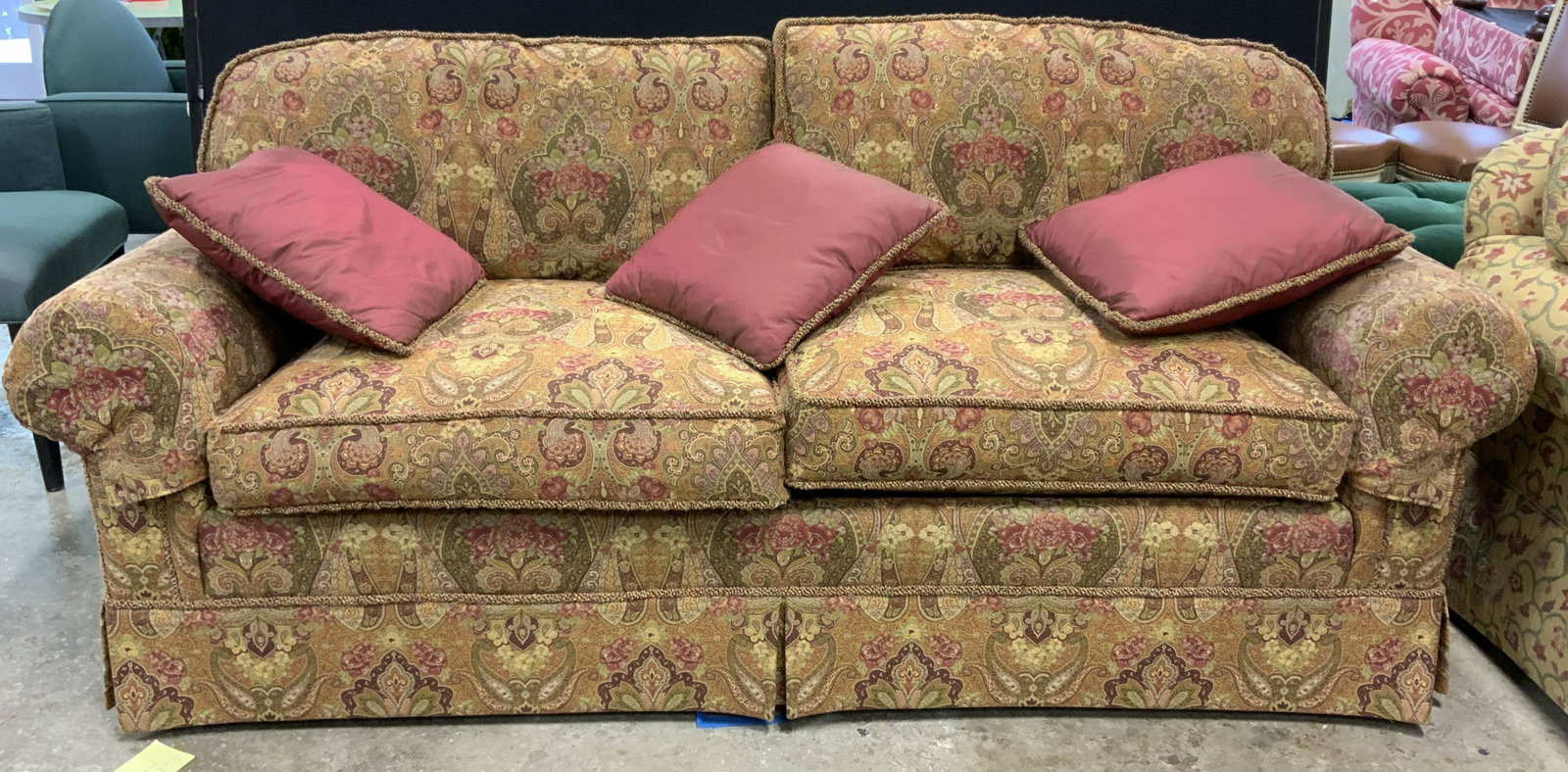 BEACON HILLS SHOWROOM Sofa: A Beacon Hill wood framed sofa, decorated with paisley print upholstery. Primarily wine red toned hues with cream, pink, and green accents. Piece has some wear consistent with use, some wear to uphols
