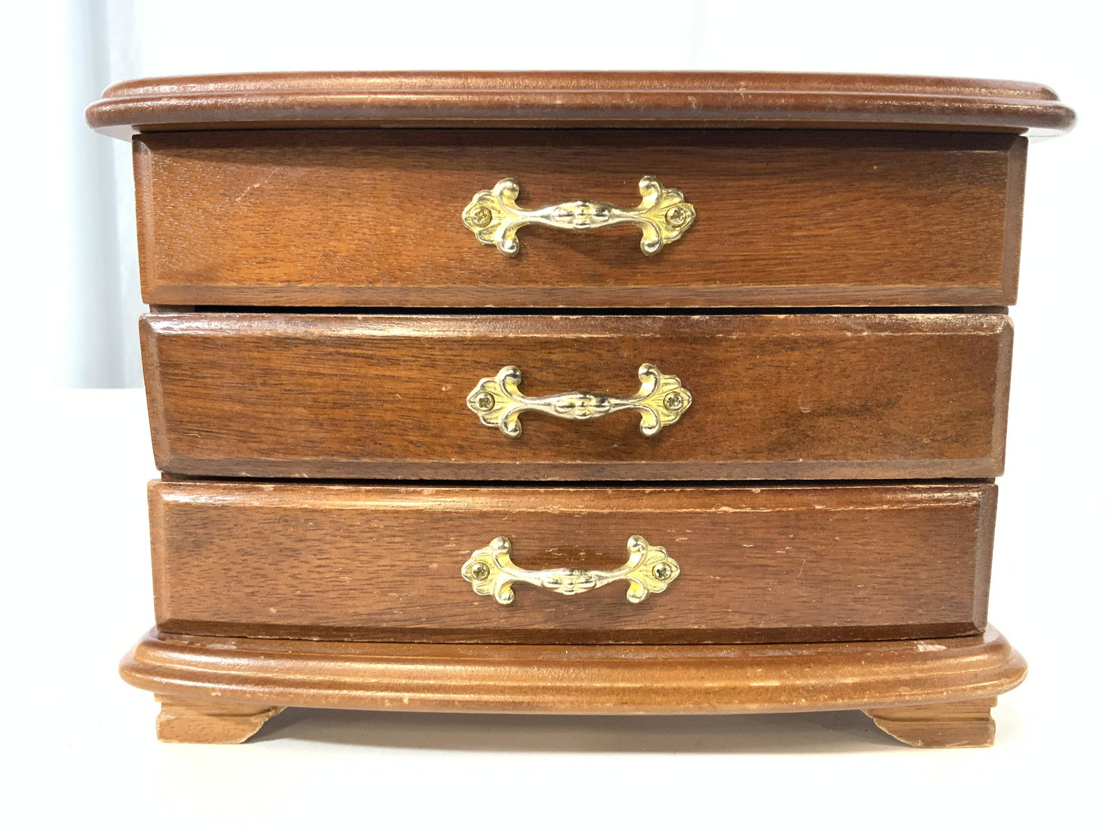 Vintage 2 Drawer Wooden Jewelry Chest: Jewelry chest is vintage. Piece is wooden with 2 drawers each with gold toned metal handles. Top of piece has hinged lid that opens up to additional storage. Piece is footed. Chest measures approx 8 i