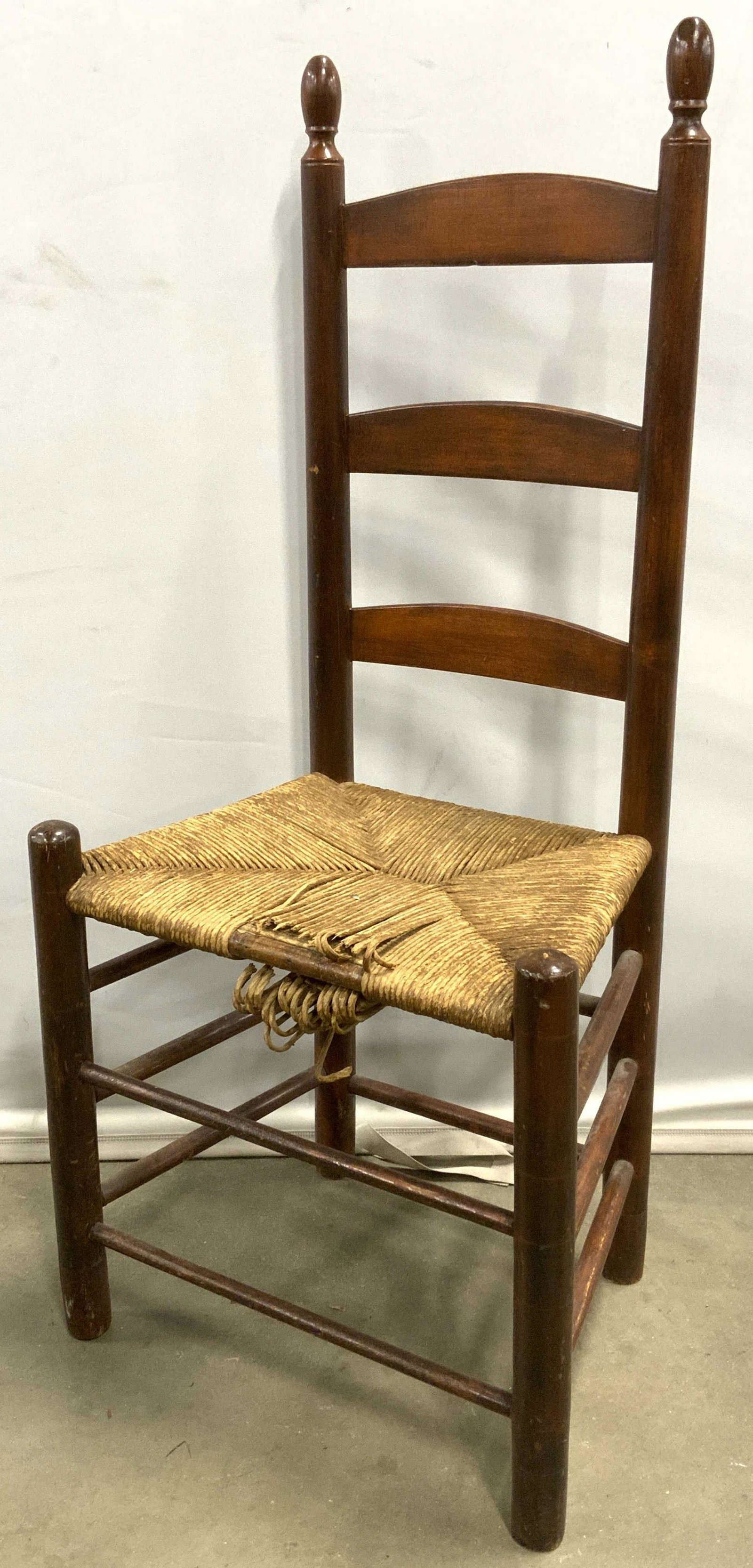 Vintage Ladder Back Chair: Vintage, possibly antique, ladder back chair. Seat is rush, legs connected by stretchers. Rush seat is damaged. Wear is otherwise consistent with age and use. Measures approx 42 inches h, 19 inches w,