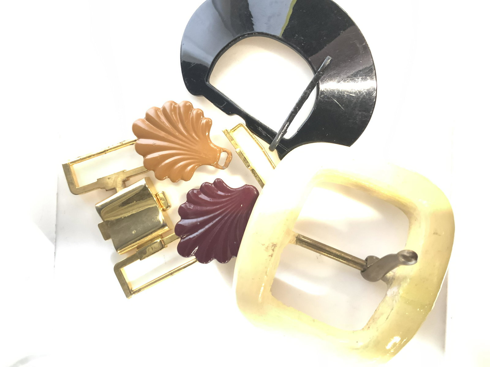 Lot 7 Variety of Vintage Belt Buckles: Turn items into beautiful art using these enameled metal scallop belt buckles ( 2 in.) , gold tone metal belt buckles, vintage Lana Goor resin oversized buckle ( 4 x 3.5 in.) and plastic black buckle.