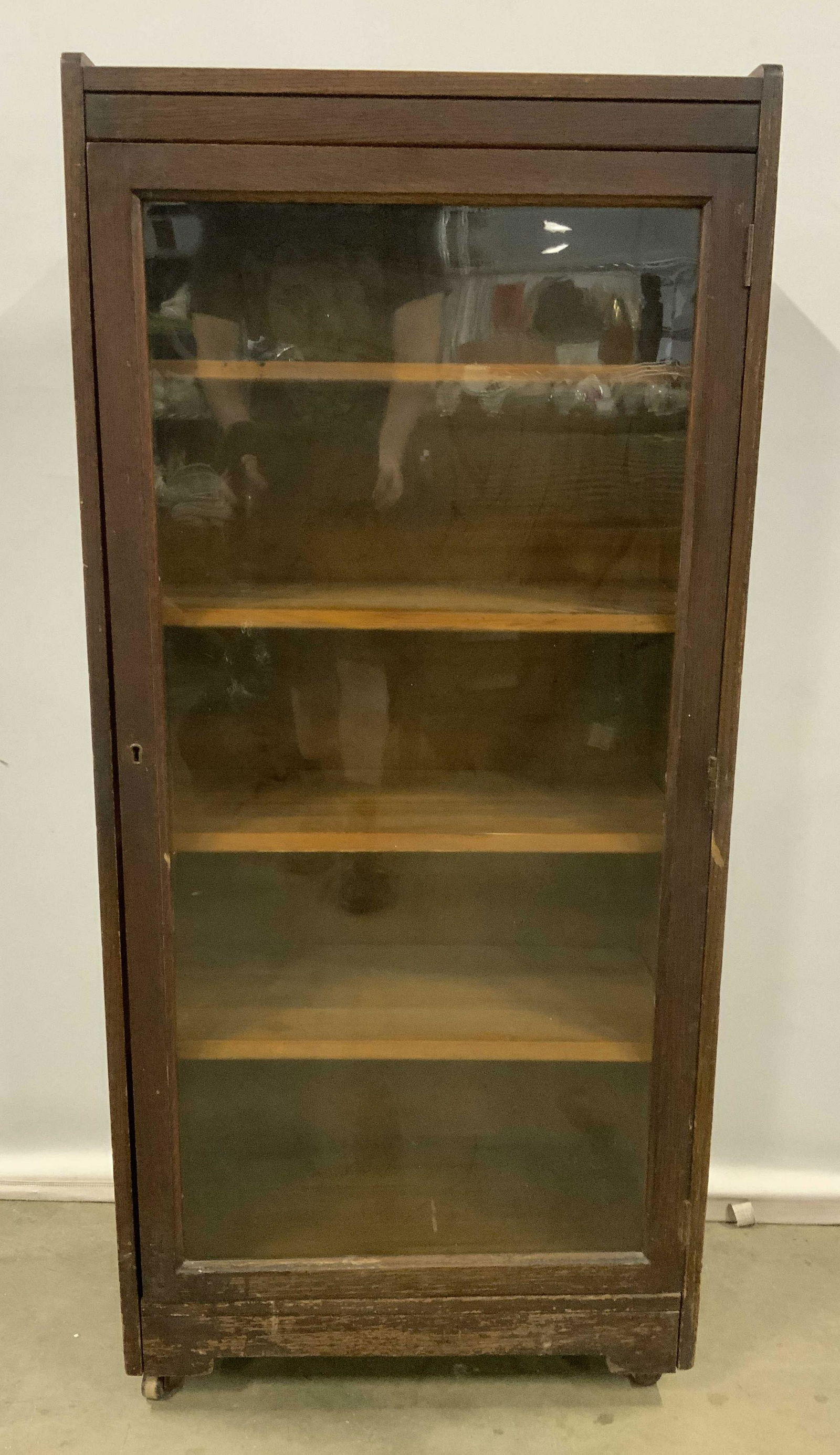 Antique Wooden Cabinet w Casters: Antique Wooden cabinet on casters, houses four shelves, door is windowed. Lock present on door, lock is functional, doesn’t lock properly, latch does not reach slot. Wear is consistent with age and