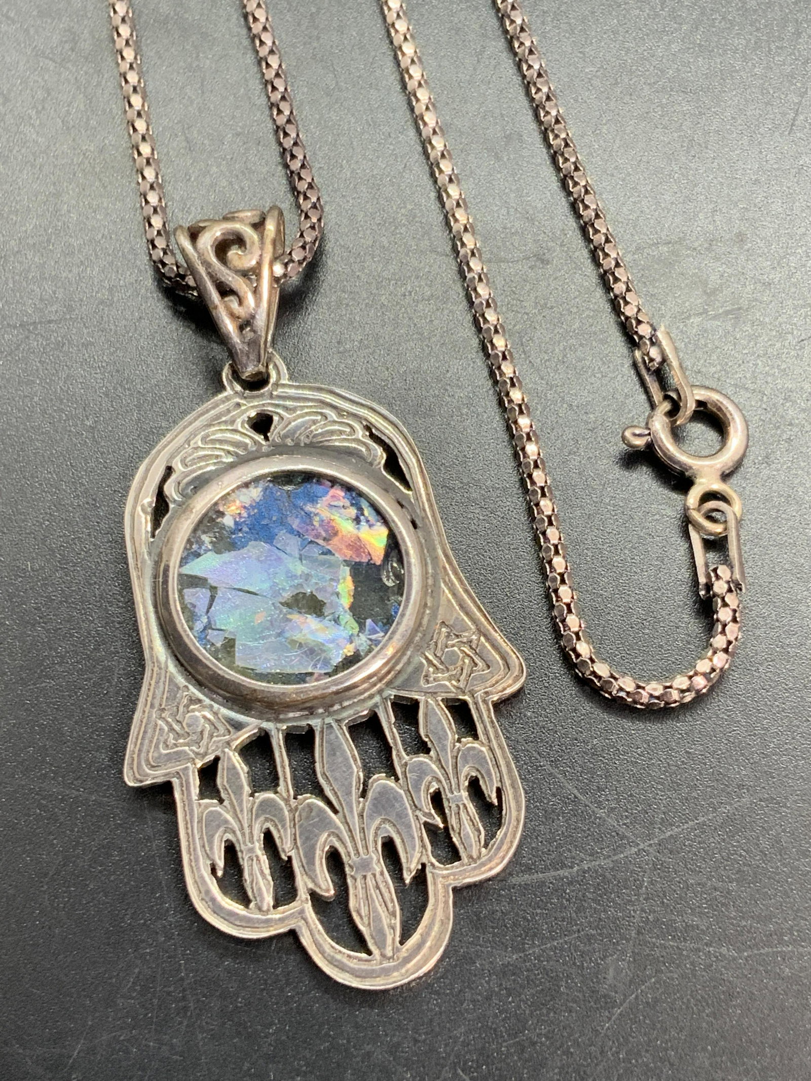 Sterling Silver Hamsa Pendant Necklace, Jewelry: A sterling silver pendant necklace. Pendant features an etched and pierced hamsa form with an iridescent resin center. The bail is marked 25, possibly a worn 925. Piece tested for high grade silver wi