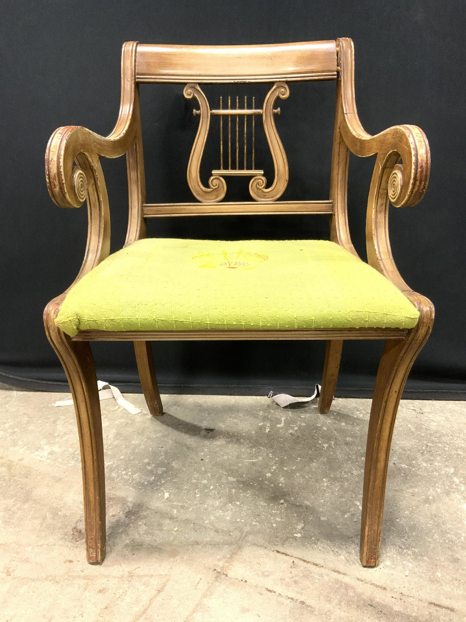 Vintage Carved Wooden Lyre Back End Chair: End chair is vintage possibly antique. Piece is wooden with carved lyre backrest. Piece has armrests which curl downwards. Seat is upholstered with green toned fabric with image of yellow shell in cen