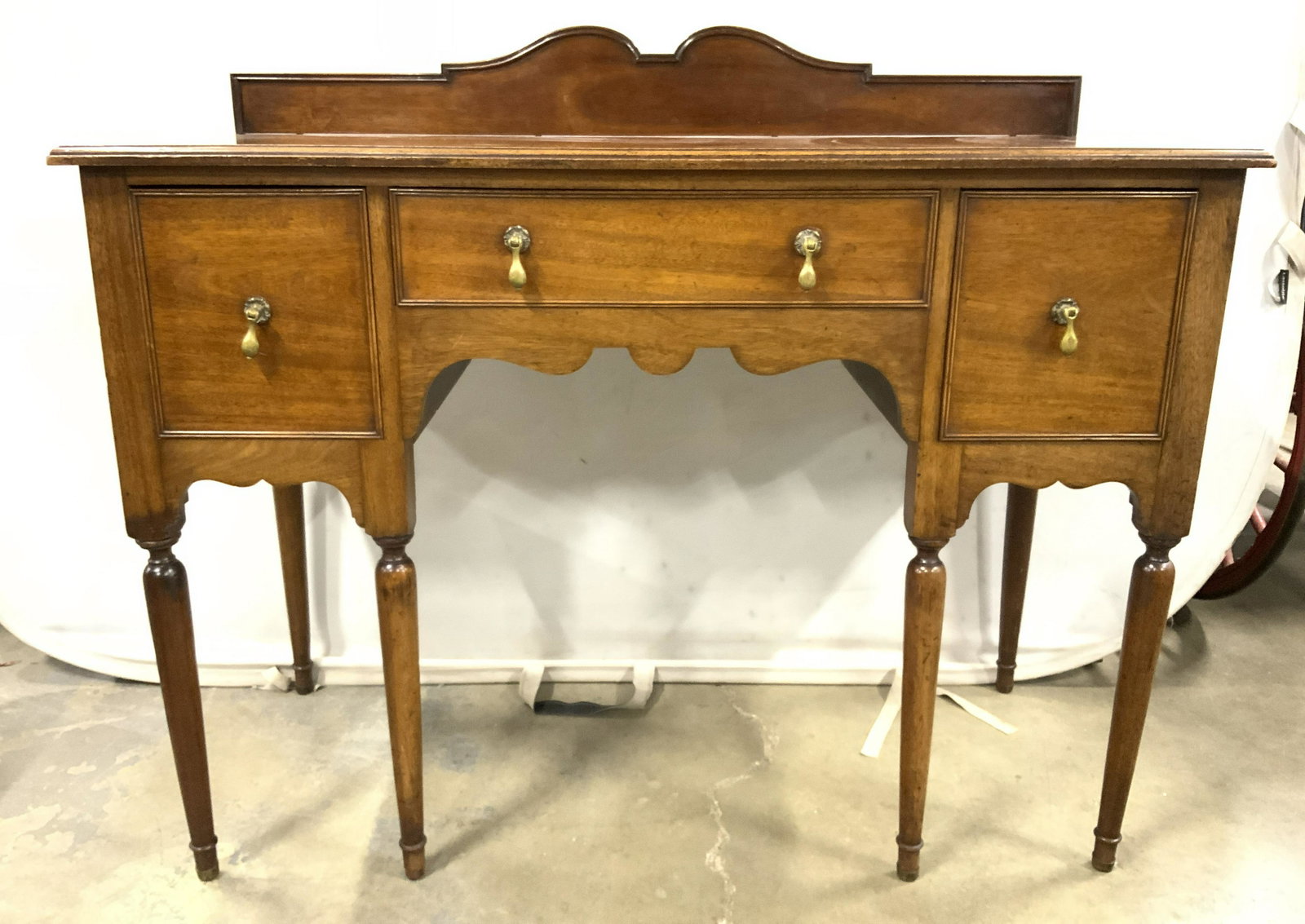 Vintage Carved Wooden Sideboard: Side board is vintage and wooden. Piece has 3 drawers each with hand dovetailing. Piece measures approx 50 inches long 42 inches tall, 21 inches deep. Drawers have dangling brass handles. Backside of 