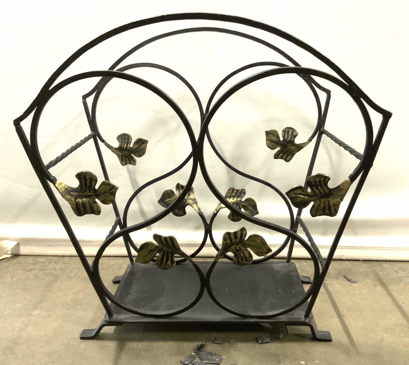 Footed Iron Magazine Rack Magazine Holder: Magazine rack is black & gold toned. Piece has s curve structures. Base has 4 feet. Piece measures approx 17.5 inches tall 17 inches wide 12 inches deep. Magazine rack, magazine holder, iron magazine 