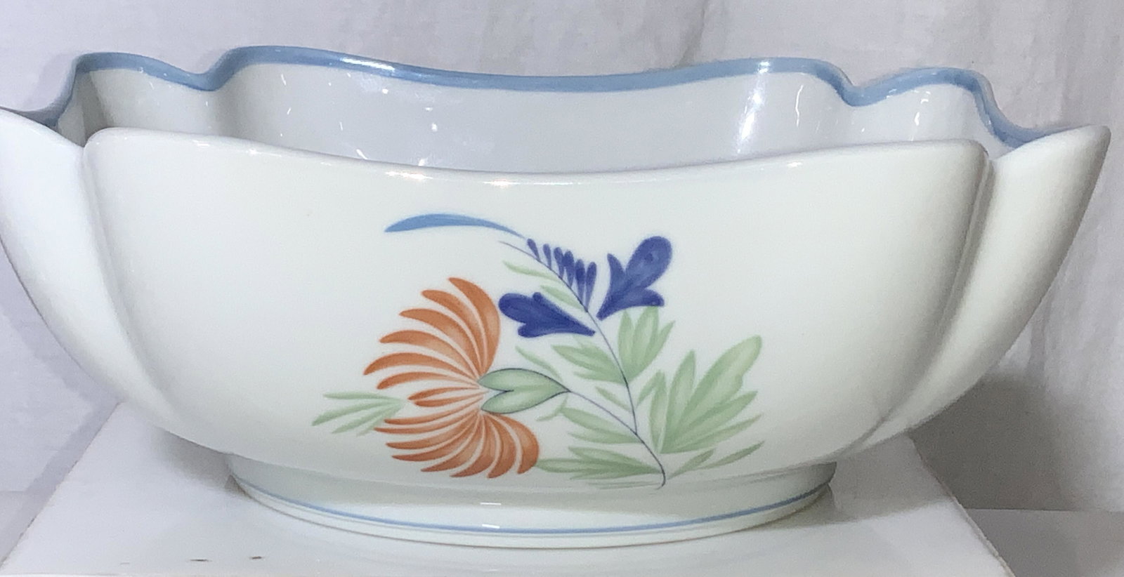 Chesterfield Haviland Limoges Porcelain Bowl: Hand made and hand painted deep dish bowl with wavy 4 corners. Minimalist French Limoges Porcelain. App 3.5 in ht, 9 in. Diameter. All white with blue rim and simple French Country Flower on one side.