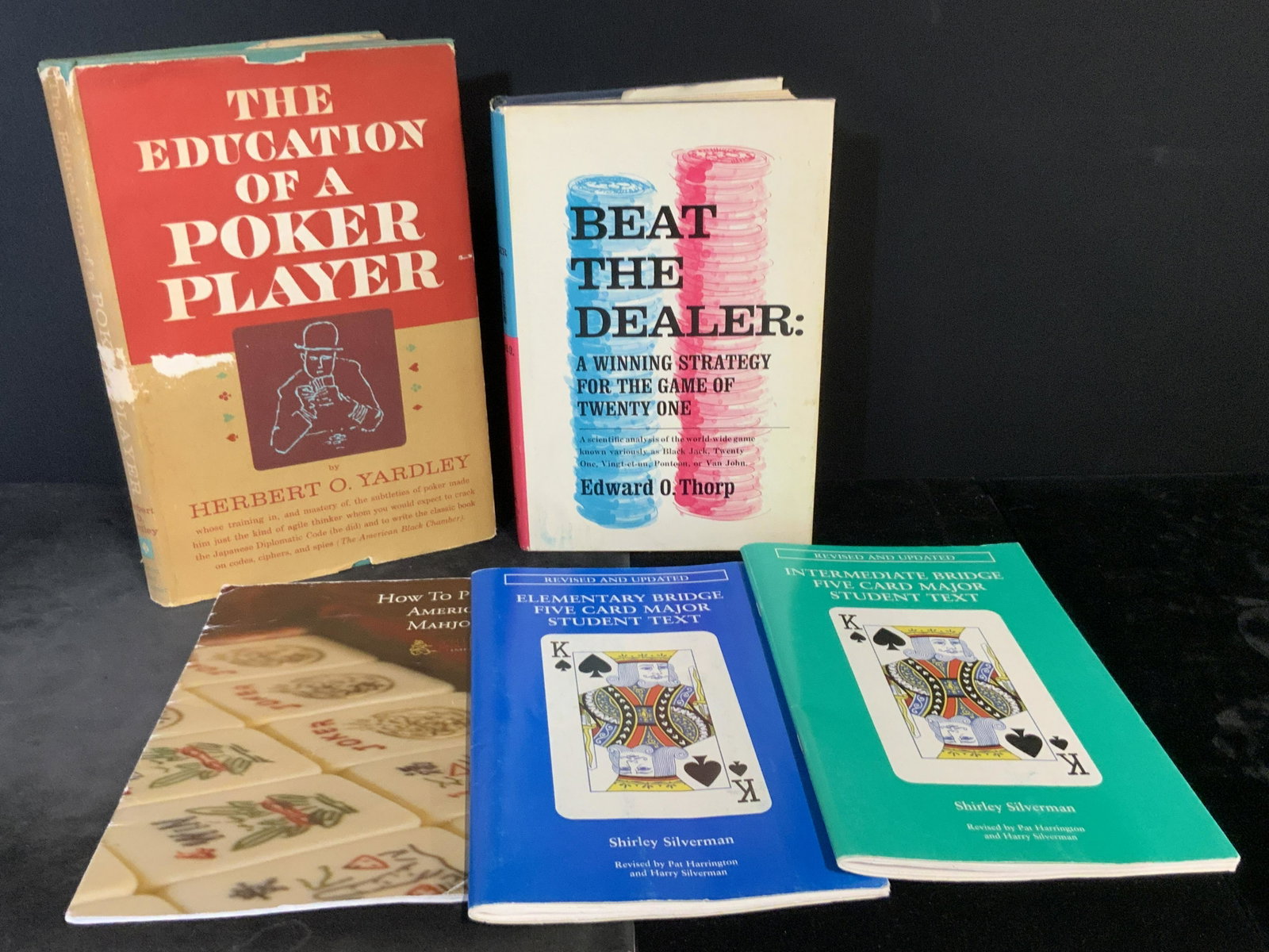Lot 5 Card Game & Poker Game Books: Five hardcover and paperback books revolving around playing cards, poker, and mahjong. Largest book measures approx. 9.5H x 6W in. Pieces possess surface wear and some losses to covers. Some writing t