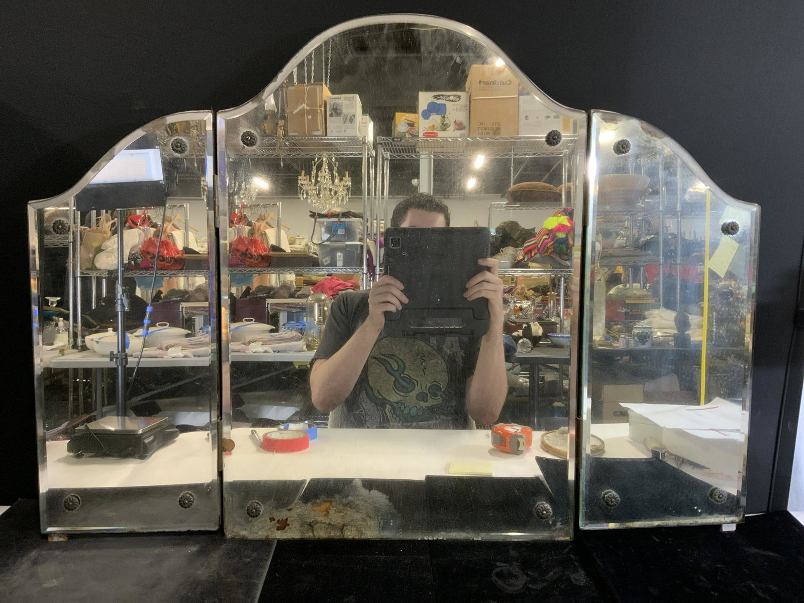 Antique Trifold Mirror: Antique trifold mirror. Mirrors are backed by wood. Wear is consistent with age and use. Screws securing mirror to backing decorated with washers cast to resemble flowers. Measures approx 25.75 inches