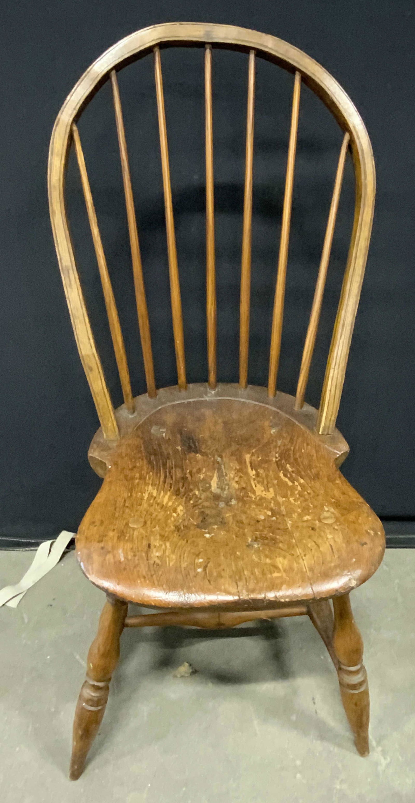 Antique Wooden Windsor Chair: An antique wooden Windsor chair. Slightly splayed legs. Spindle backing. Piece has evident signs of wear consistent with age and use. Some discoloration. Approx. 38 in. height x 18 in. width x 18 in.