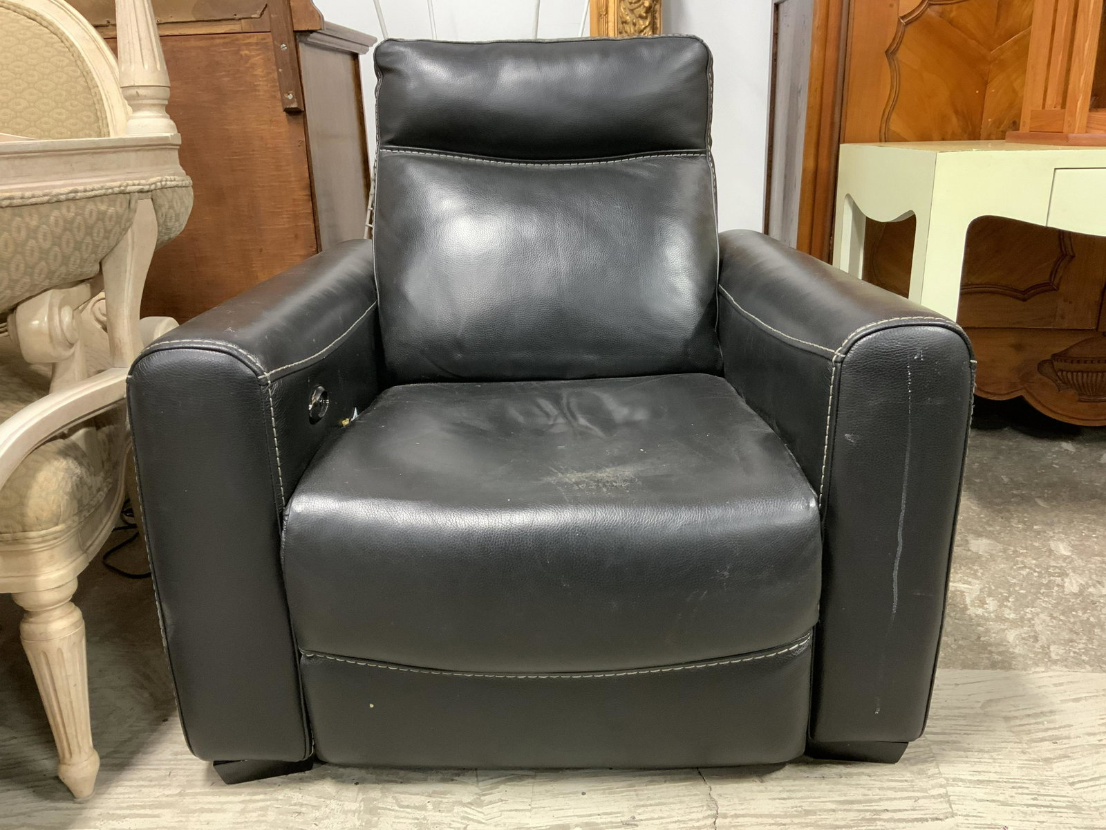Vintage Black Leather Recliner: Recliner is black toned and appears to be genuine leather. Piece has 4 black toned feet. Recliner appears to possibly be motorized due to electrical wire. Piece measures approx 38 inches tall and long