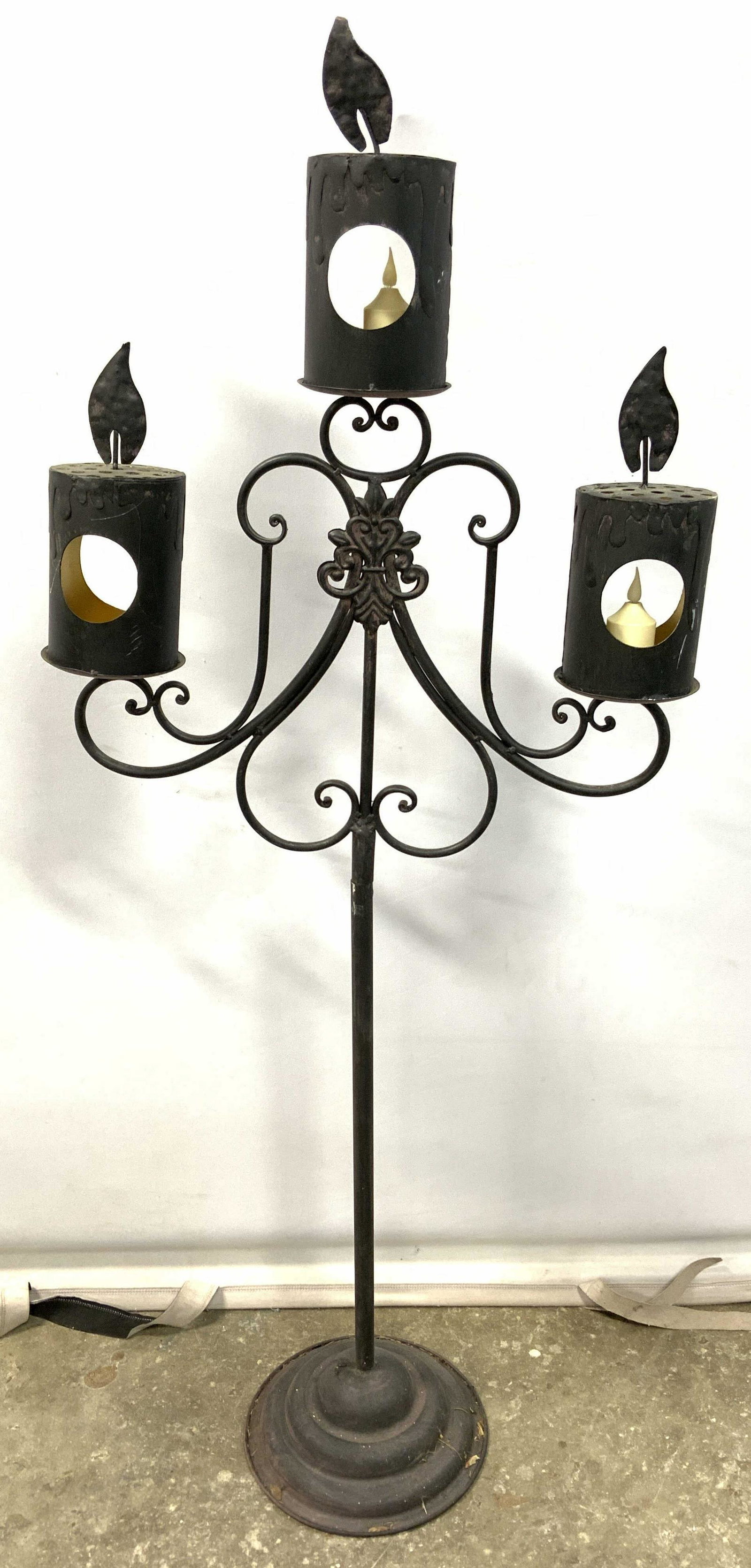 Halloween Standing Three Arm Candelabra: Candelabra is black toned and metal. Piece has circular shaped base & 3 arms. Piece has flame shaped structures at top. Piece measures approx 51 inches tall 20 inches wide 10 inches deep. Candelabra, 