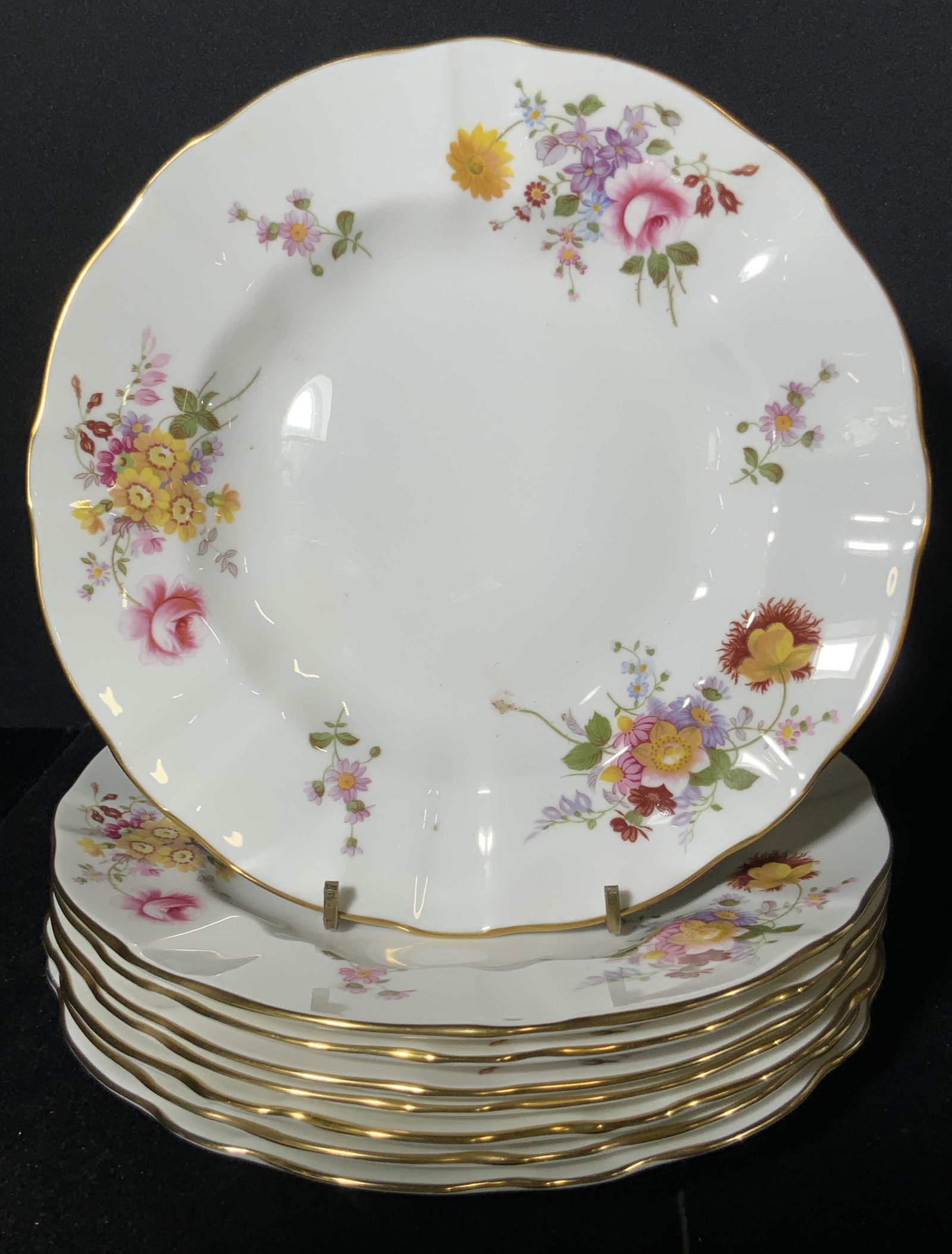 Set 8 ROYAL CROWN DERBY English Bone China Plates: White plates with gilt line work and florals throughout the obverse. Derby Posies pattern. Rim has a slight scallop. Pieces measure approx 9 x 9 in. Underside reads ROYAL CROWN DERBY, English Bone Chi