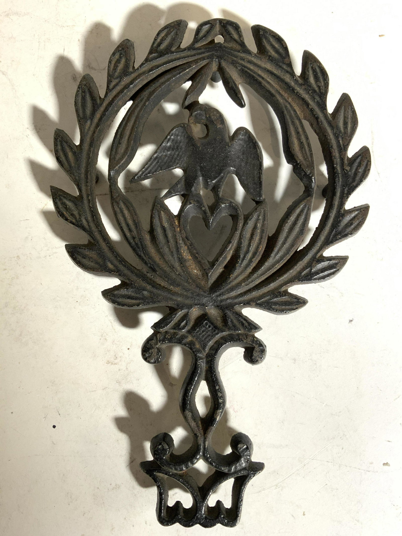 Vintage Iron Trivet W Leaf & Bird Detail: Trivet is vintage possibly antique. Piece appears to be iron. Trivet has leaf & bird structures. Piece has 4 feet. Trivet measures approx 8.5 inches long 5.5 inches wide. Trivet, iron trivet, Vintage 
