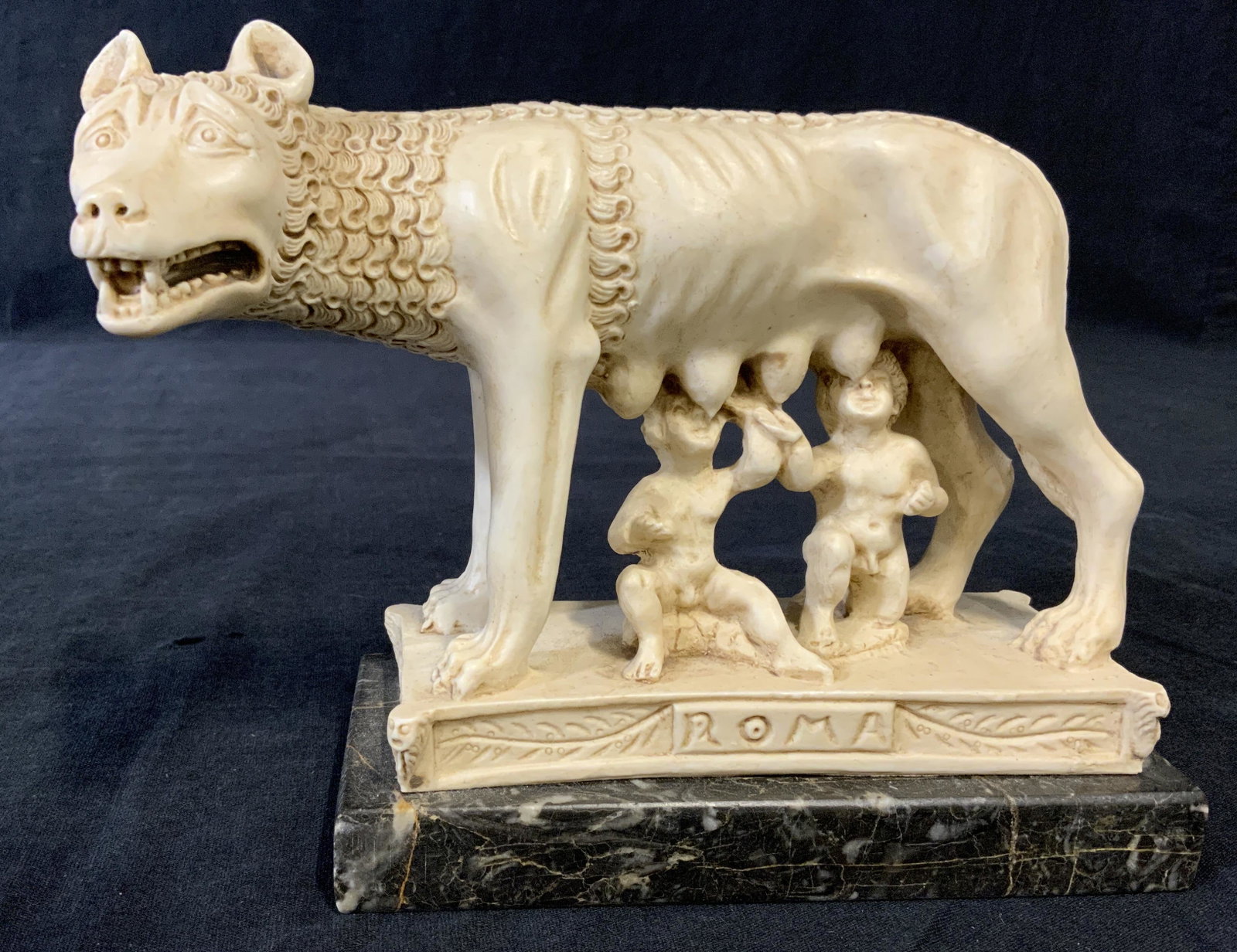Sculpted Romulus & Remus Resin: Sculpted Romulus & Remus resin sculpture. Base is marble, depicts Romulus and Remus feeding from a wolf, reads Roma. Measures 5.25 inches and 7.25 inches W. Wear is consistent with age and use. Resin 