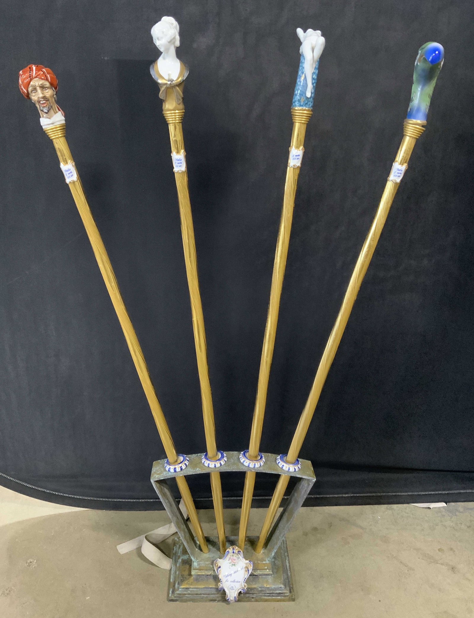 Set 4 TICHE Brass & porcelain walking Sticks: Set of 4 brass canes with stand. Stand and shafts of each cane are brass. Ceramic medallion on stand reads as WALKING STICK RACK FOR COLLECTION, PORCELAINE D ART FAIT ALA MAIN MILAN. Handles depict a 